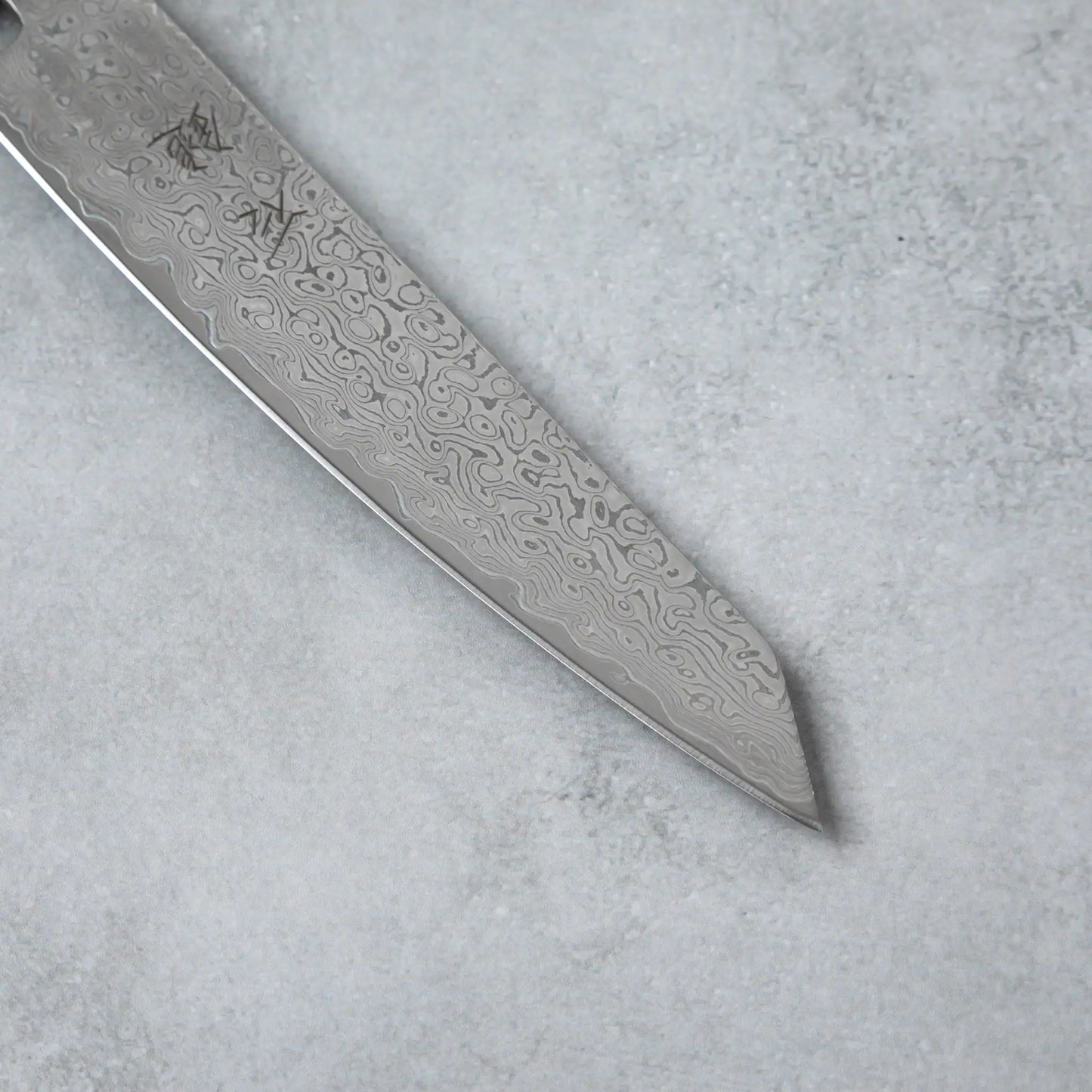 Zoomed-in view of the sharp edge and tip of the Ishizuchi VG10 Damascus Petty Knife, emphasizing the blade's precision and elegant Damascus pattern.