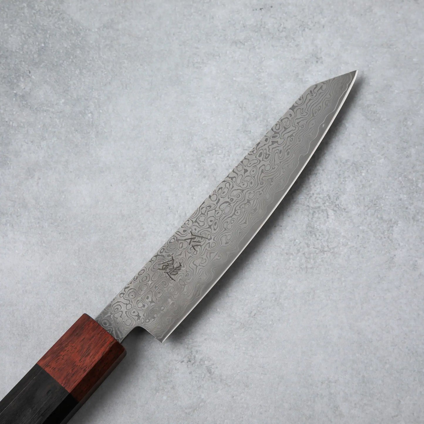 Close-up of the Damascus steel blade on the Ishizuchi VG10 Petty Knife, featuring intricate wave-like patterns and kanji engravings.