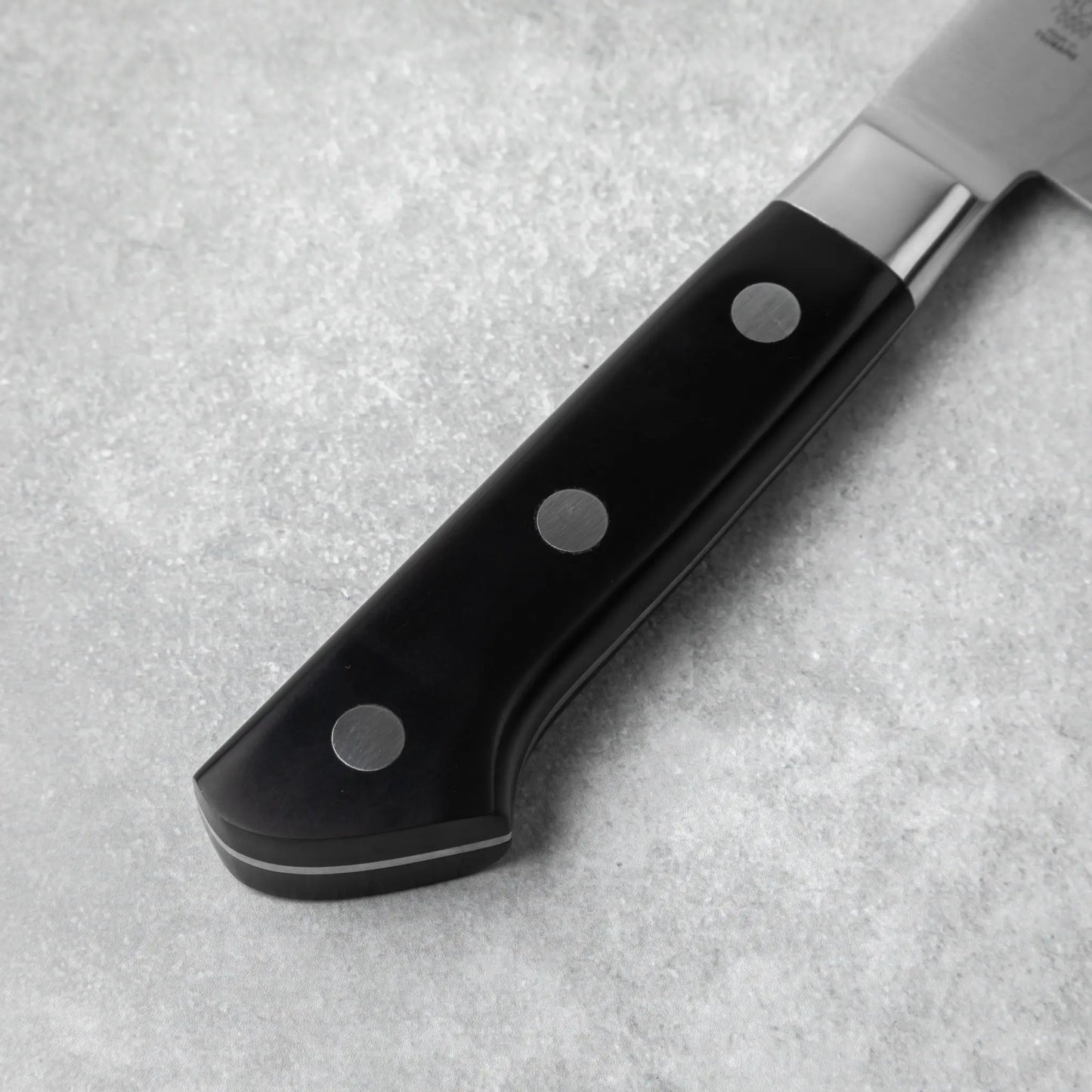 The triple-riveted black handle, crafted for durability and comfort during use.