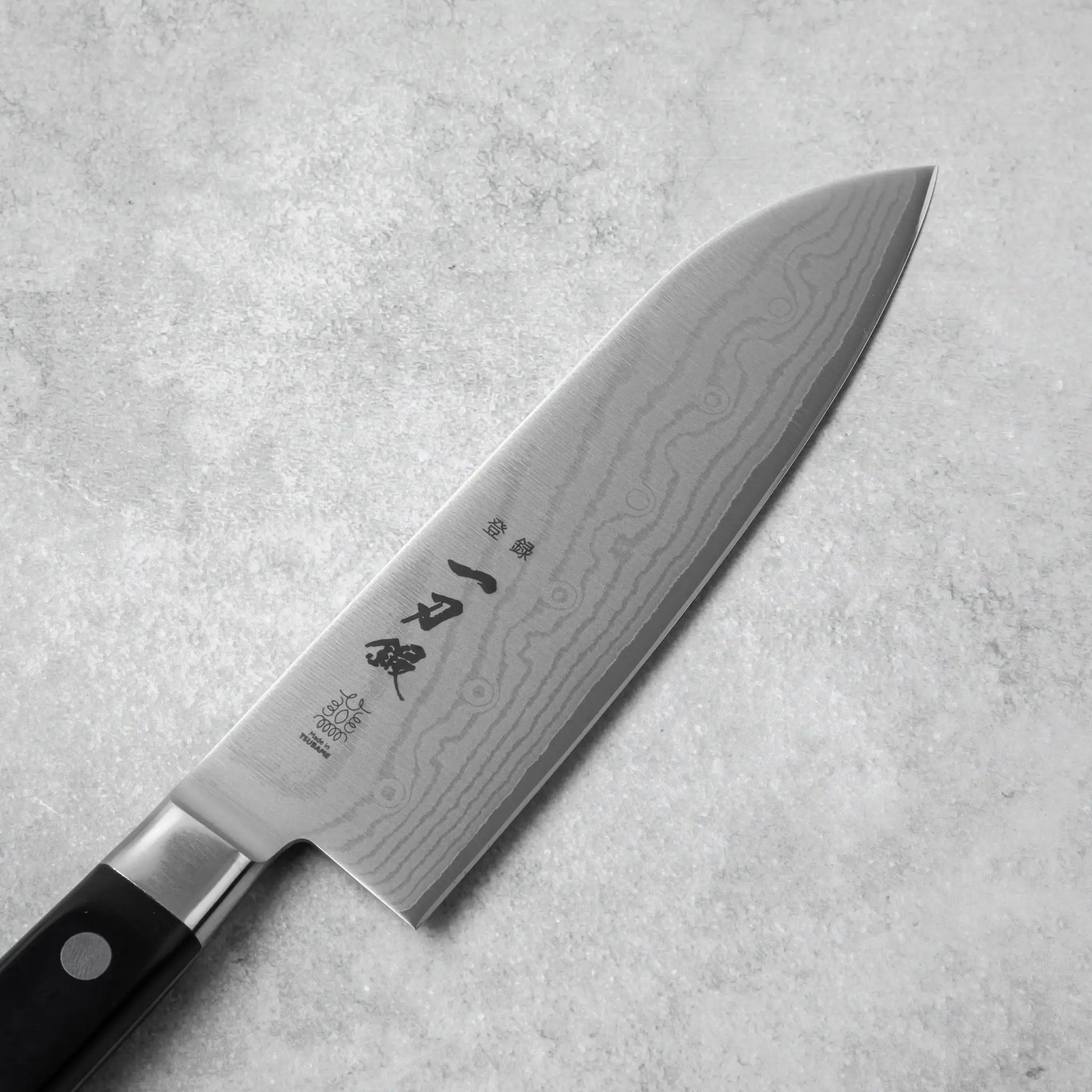 A close-up of the Santoku knife’s blade, showcasing the elegant Damascus pattern.