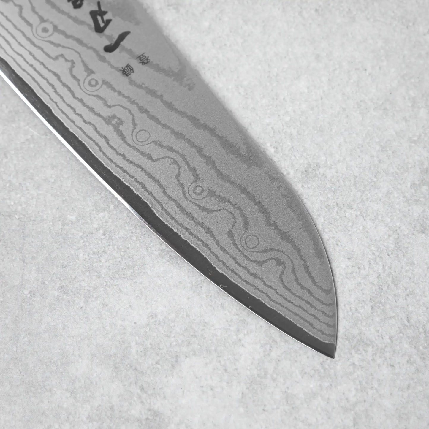 A macro shot of the finely honed Santoku knife’s edge, highlighting its sharpness.