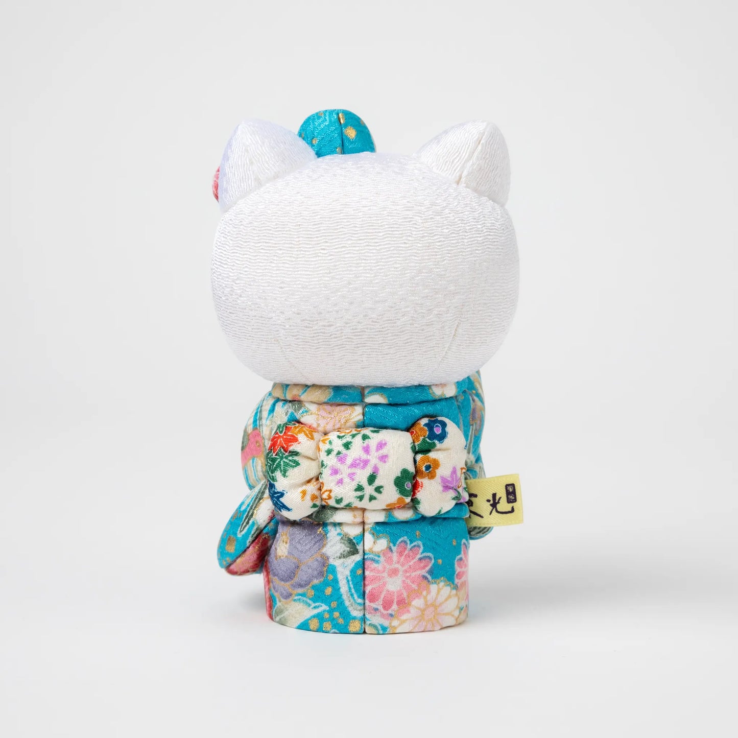 Back view of the Edo Kimekomi Kimono Maneki Hello Kitty Blue, revealing the detailed bow and floral patterns on the kimono, symbolizing the Edo Kimekomi doll craftsmanship.