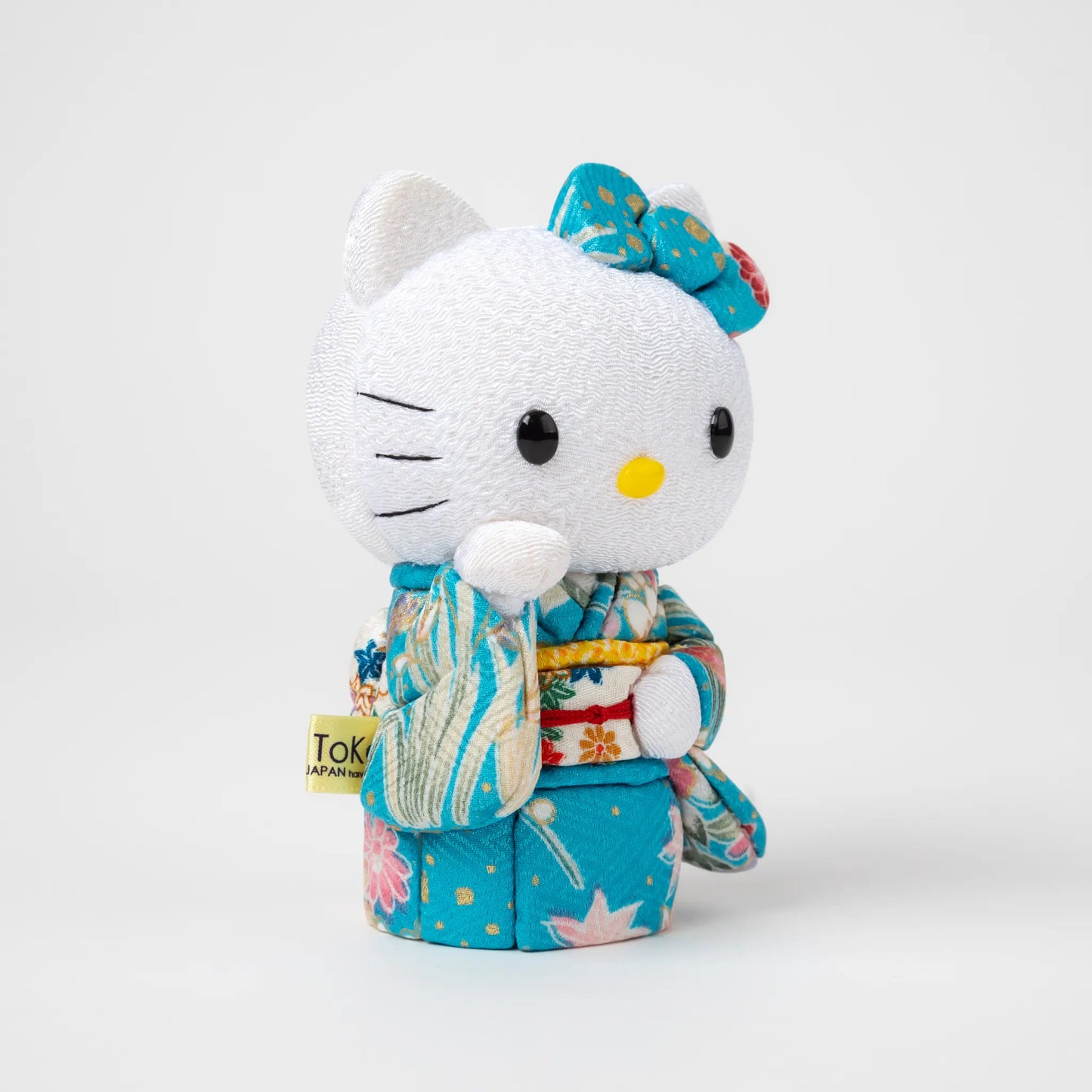 Angled view of the Edo Kimekomi Kimono Maneki Hello Kitty Blue, highlighting the traditional fabric texture and floral design of the kimono, with Hello Kitty’s arm raised in a welcoming gesture.