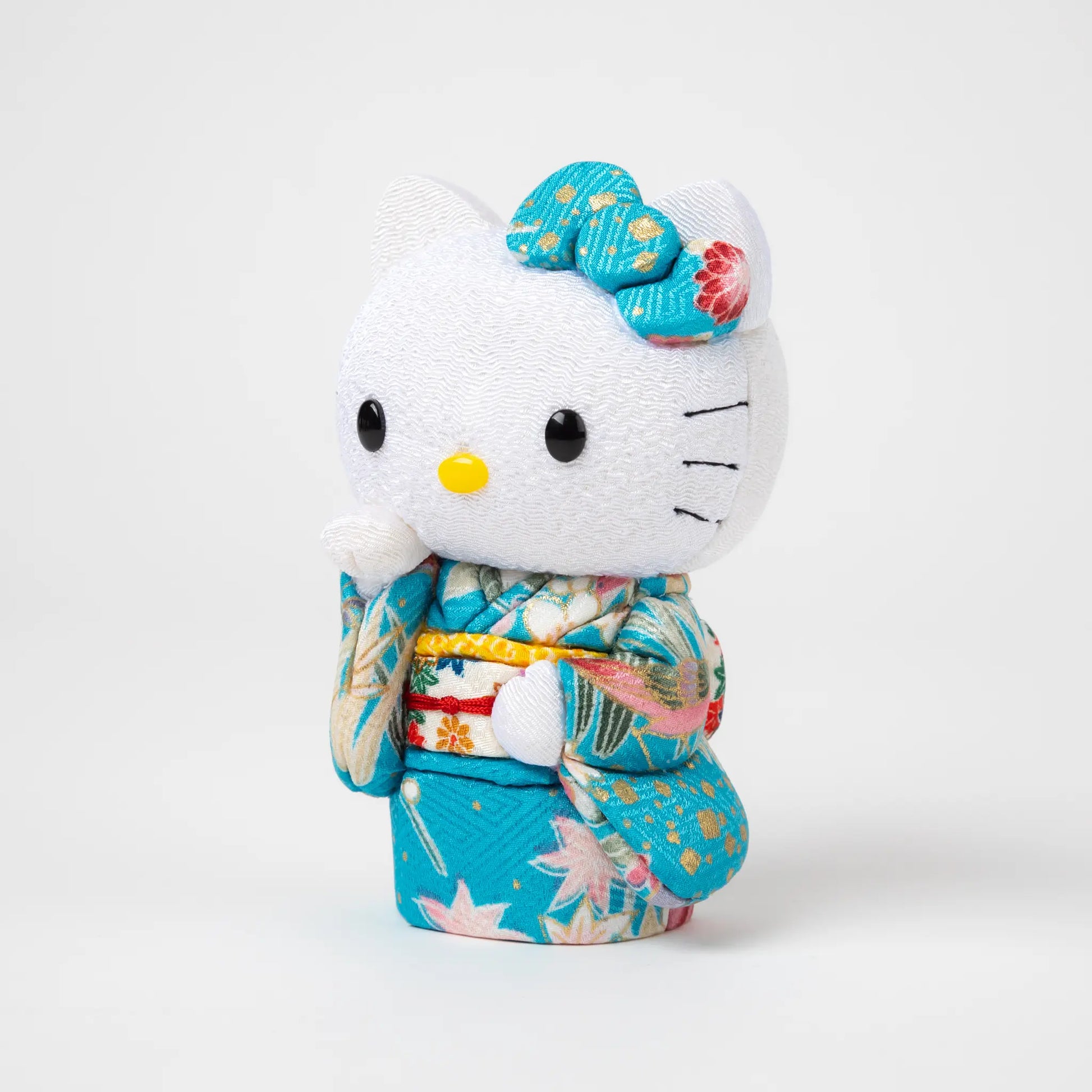 Side view of the Edo Kimekomi Kimono Maneki Hello Kitty Blue, showcasing intricate details of the floral-patterned kimono and a label indicating 'Toko Japan' attached to the kimono.