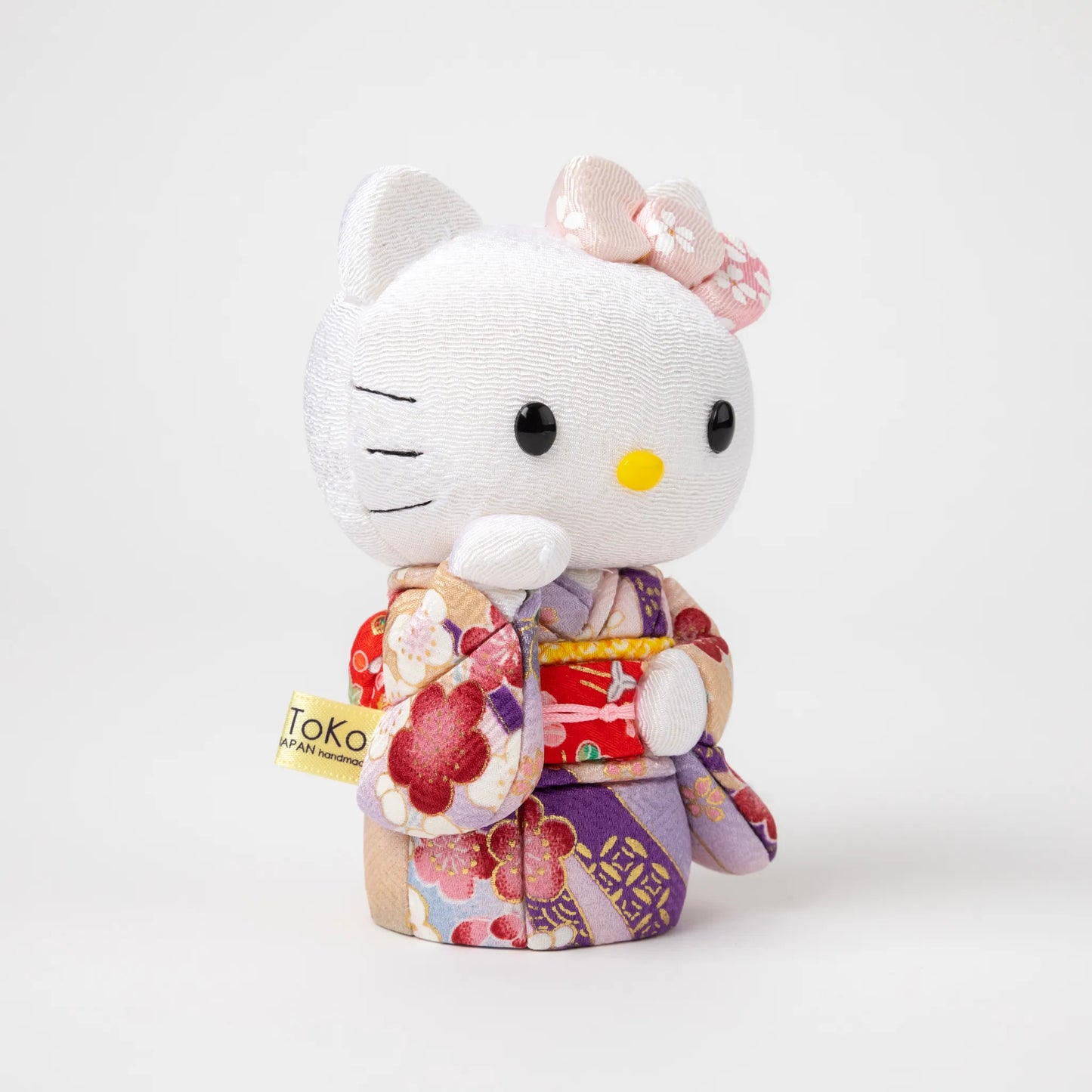 Angled view of the Edo Kimekomi Kimono Maneki Hello Kitty Pink, highlighting the traditional fabric texture and floral design of the pink kimono, with Hello Kitty’s arm raised in a welcoming gesture.