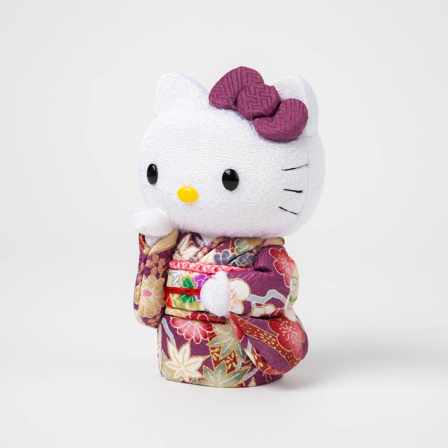 Side view of the Edo Kimekomi Kimono Maneki Hello Kitty Purple, showcasing intricate details of the floral-patterned purple kimono and a label indicating 'Toko Japan' attached to the kimono.