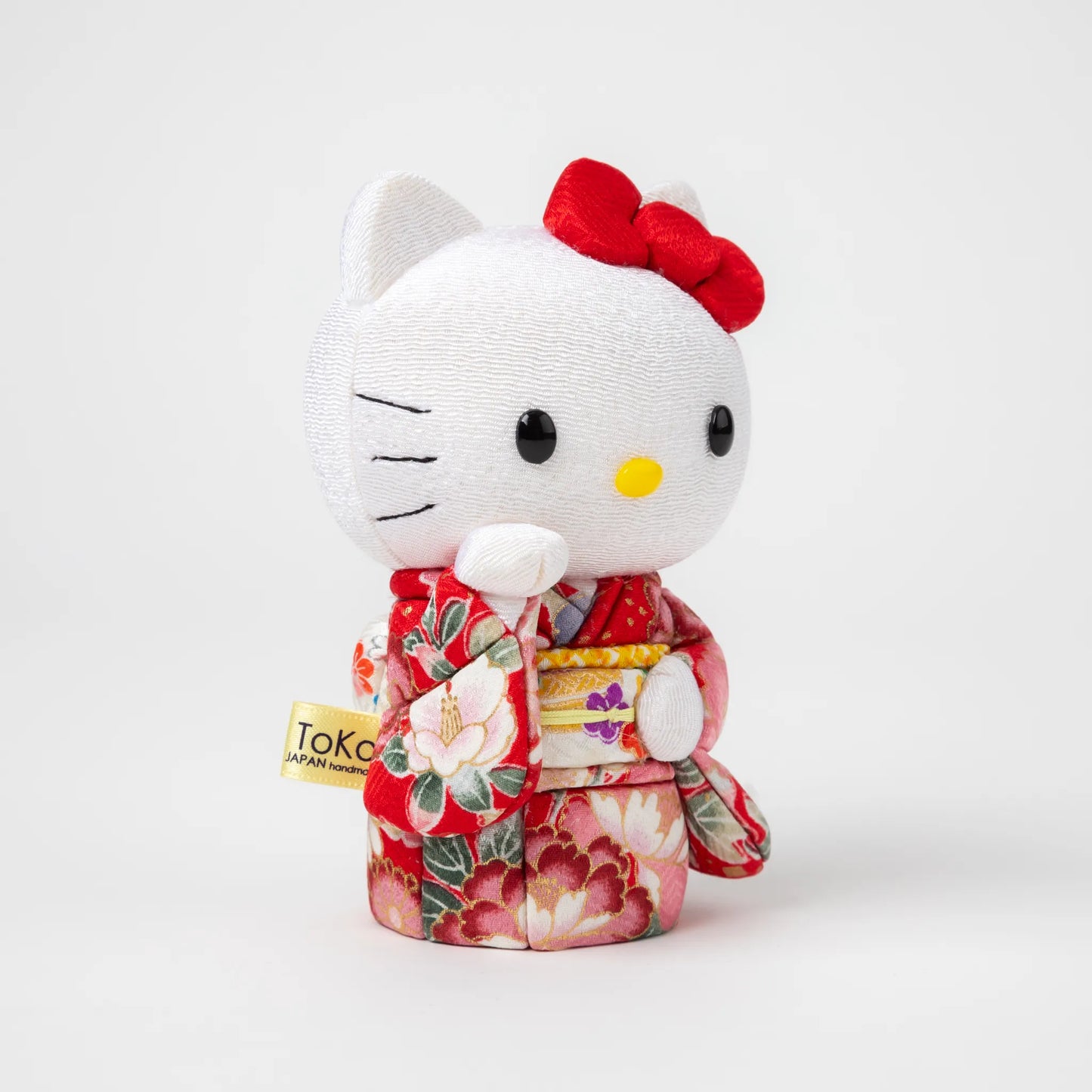 Angled view of the Edo Kimekomi Kimono Maneki Hello Kitty Red, highlighting the traditional fabric texture and floral design of the red kimono, with Hello Kitty’s arm raised in a welcoming gesture.