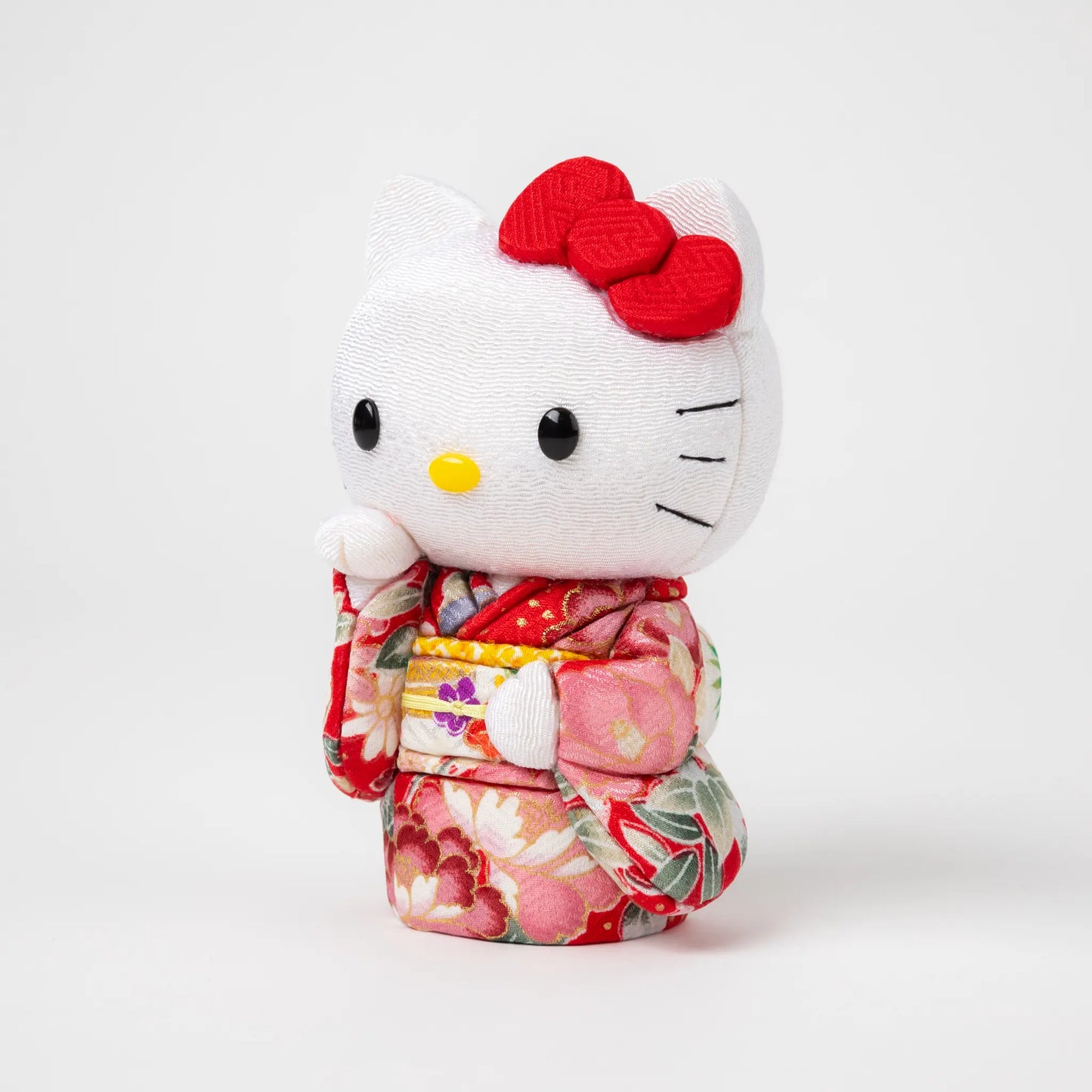 Side view of the Edo Kimekomi Kimono Maneki Hello Kitty Red, showcasing intricate details of the floral-patterned red kimono and a label indicating 'Toko Japan' attached to the kimono.