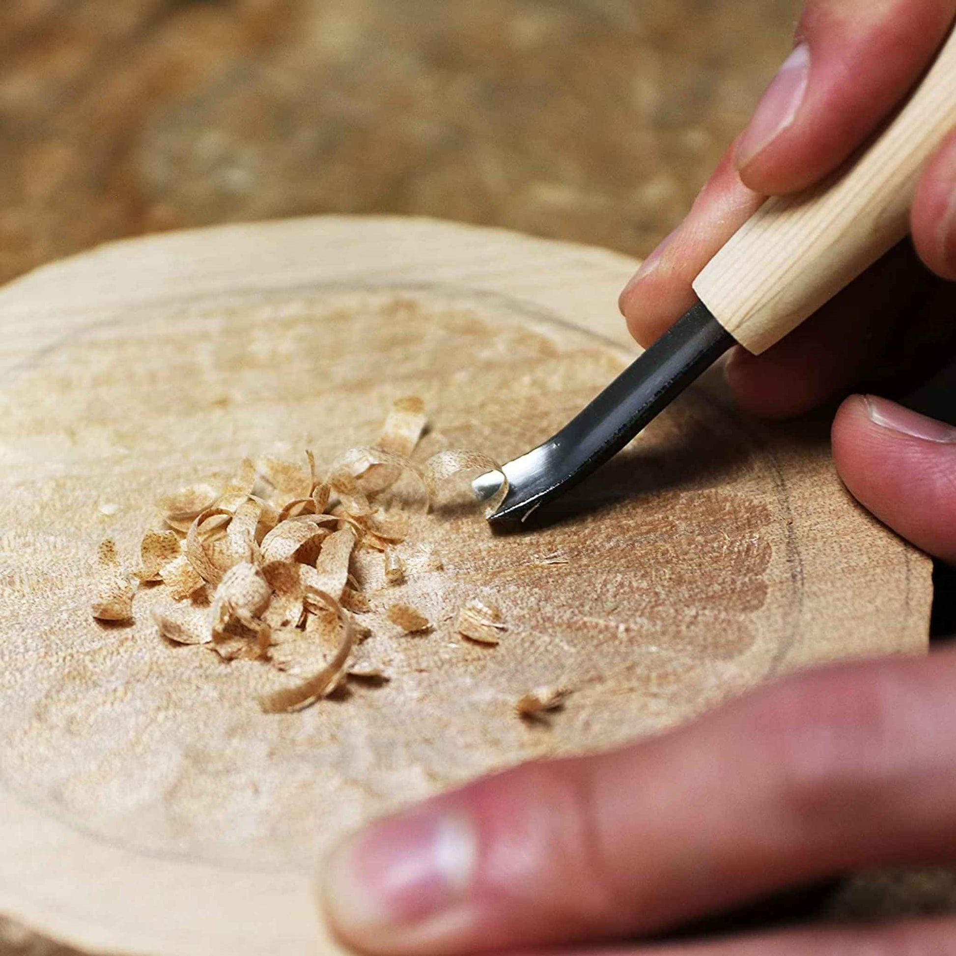 Close-up of Kakuri Aogami steel wood carving knife being used to carve intricate wooden details, highlighting the sharpness and precision of the blade.