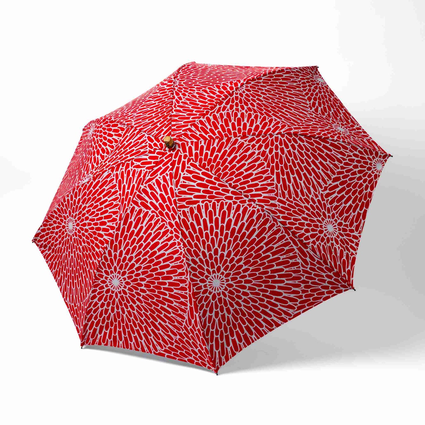 Isa Moyō Folding Umbrella fully opened, showcasing the bold Chrysanthemum motif against a red background.