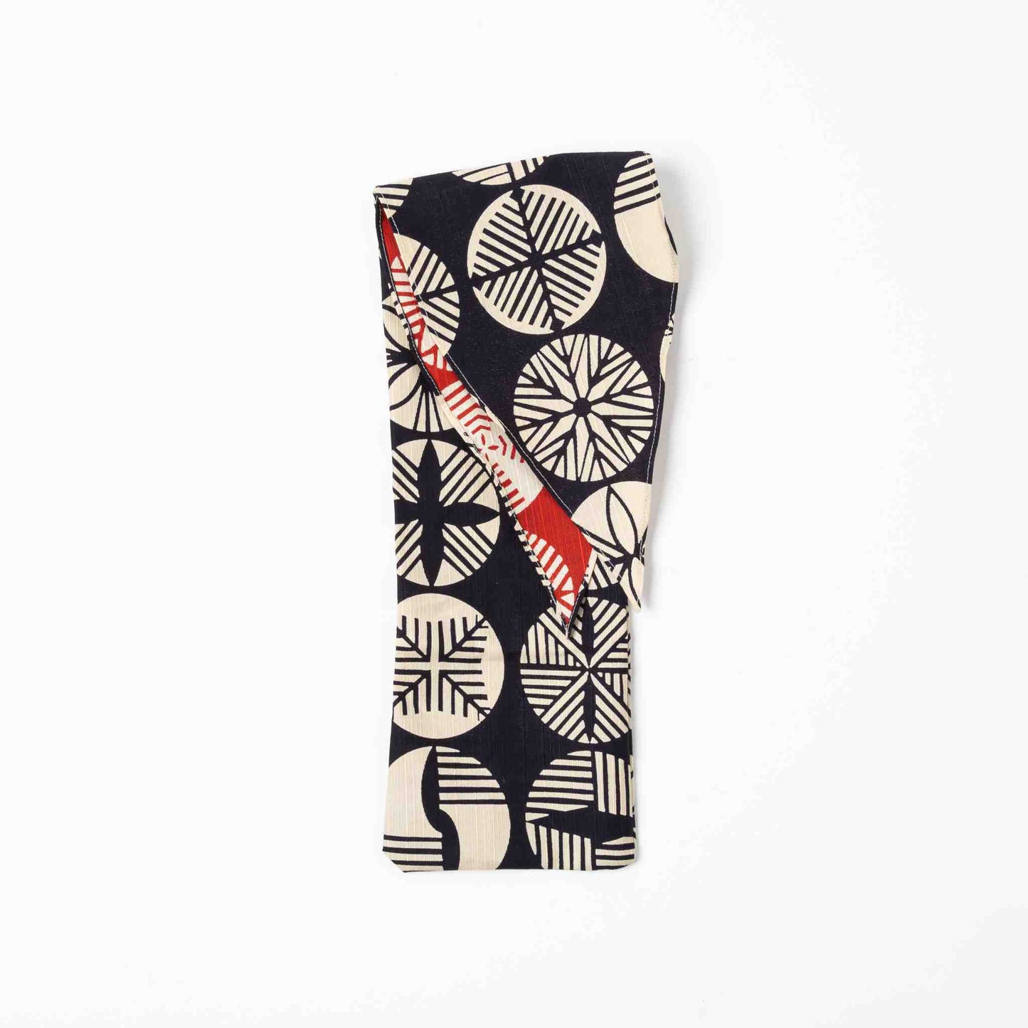 A folded Isa Moyō Folding Umbrella pouch featuring the Pine Tree motif in dark navy and cream, with a glimpse of the contrasting red inner lining.