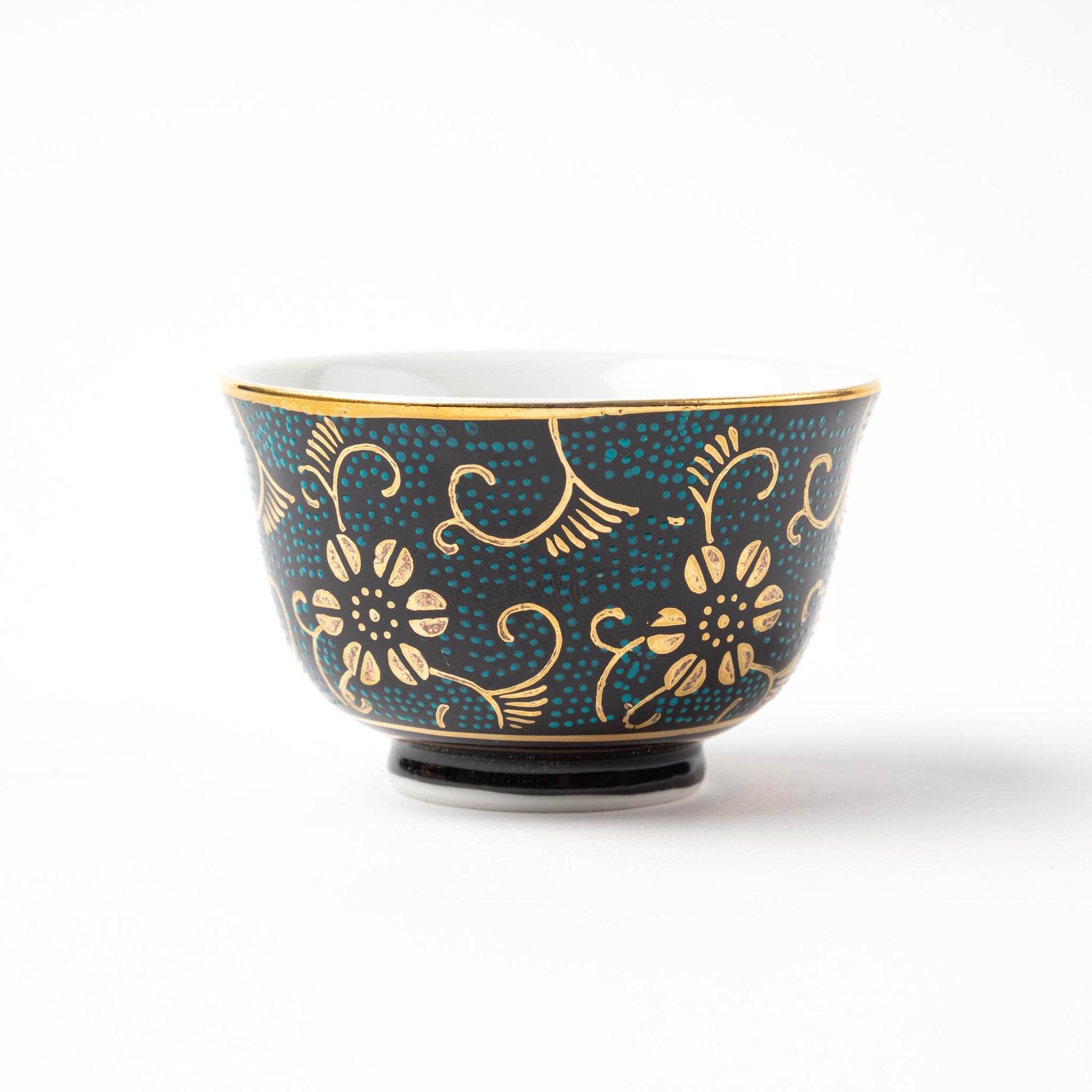 Close-up of a Kutani Aochibu Tessen tea cup, decorated with gold floral motifs and a turquoise dotted pattern over a dark blue background.