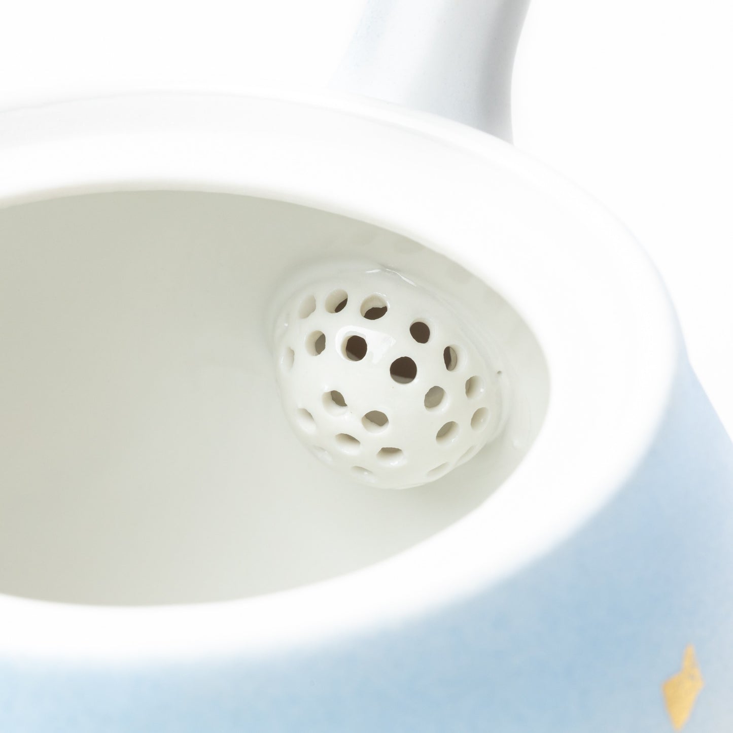 Close-up view of the porcelain tea strainer inside the Kutani Mountain Range teapot