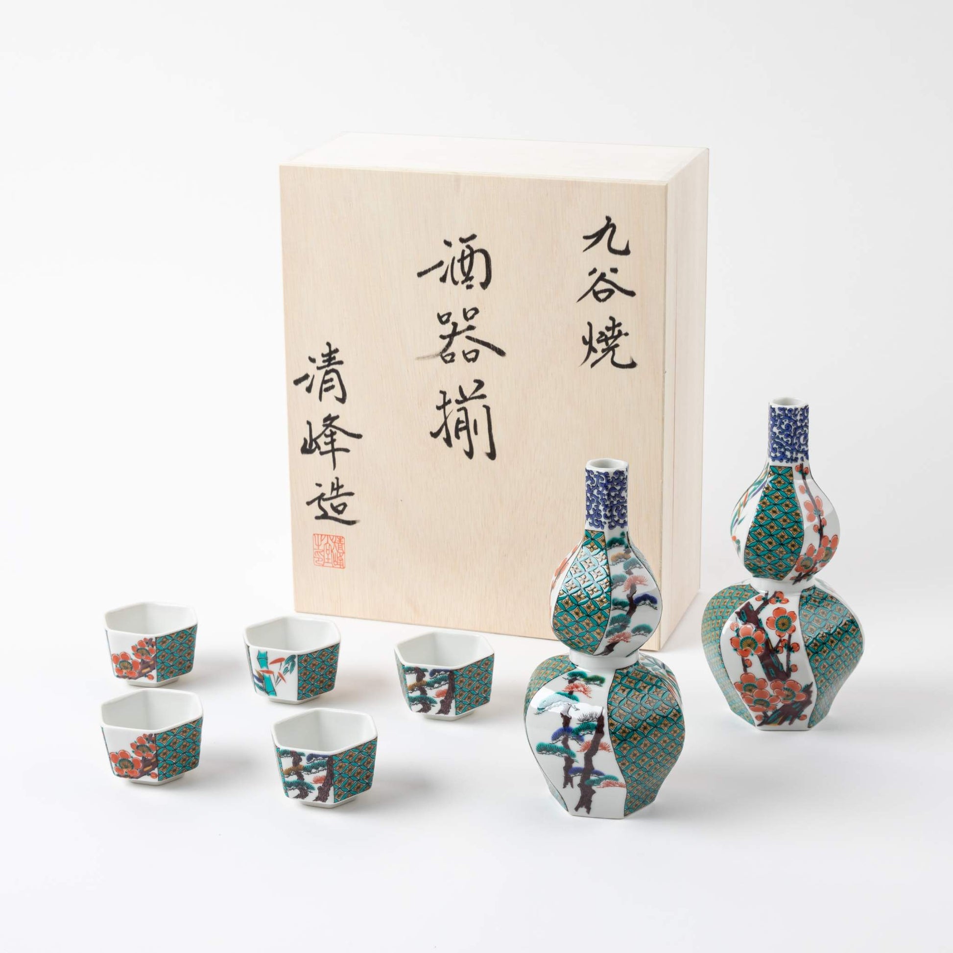 Elegant Kutani sake set featuring hexagonal cups and two gourd-shaped bottles, adorned with intricate pine, bamboo, and plum motifs, accompanied by a wooden gift box.