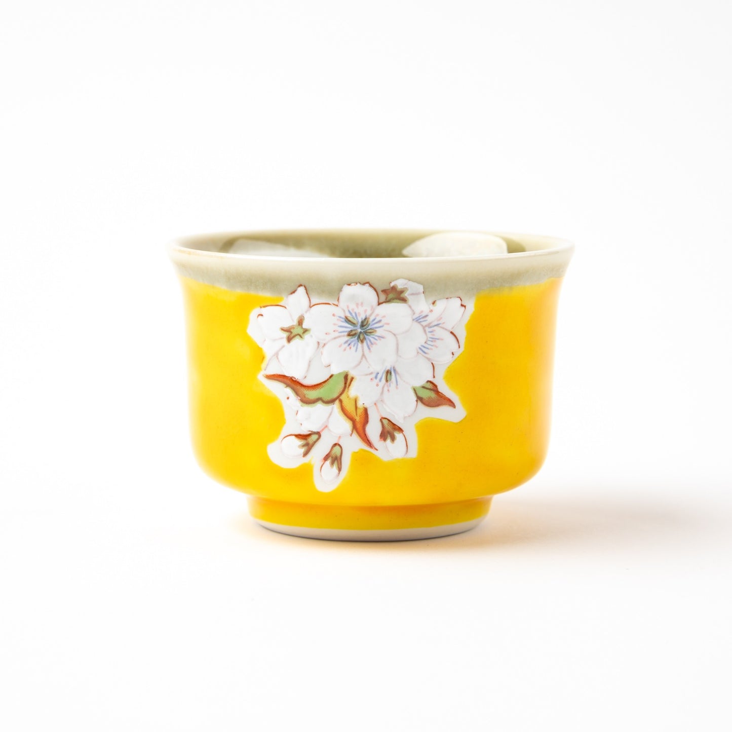 A close-up of one yellow sake cup featuring a detailed hand-painted cherry blossom design.