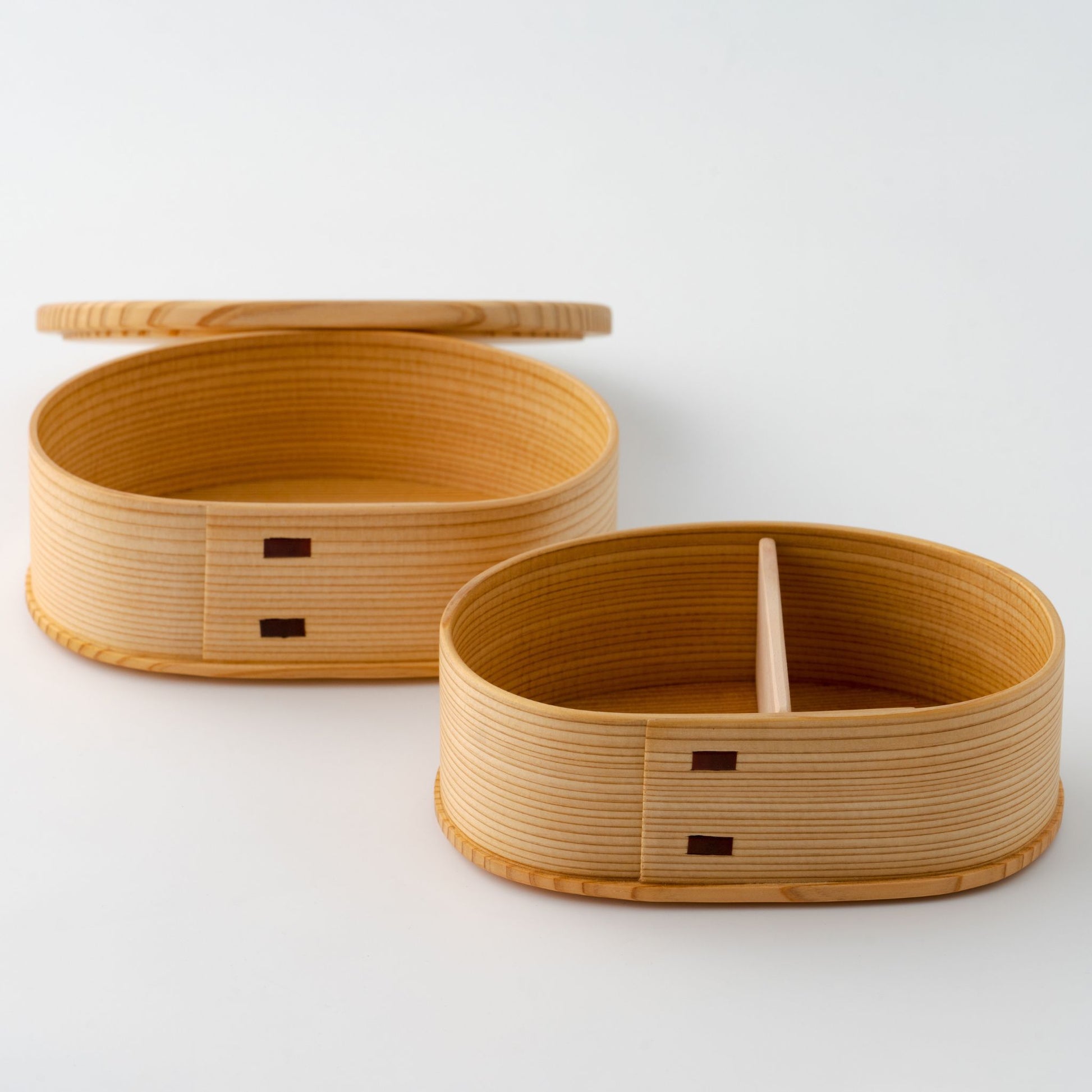 A small wooden bento box with one tier open, revealing divided compartments.