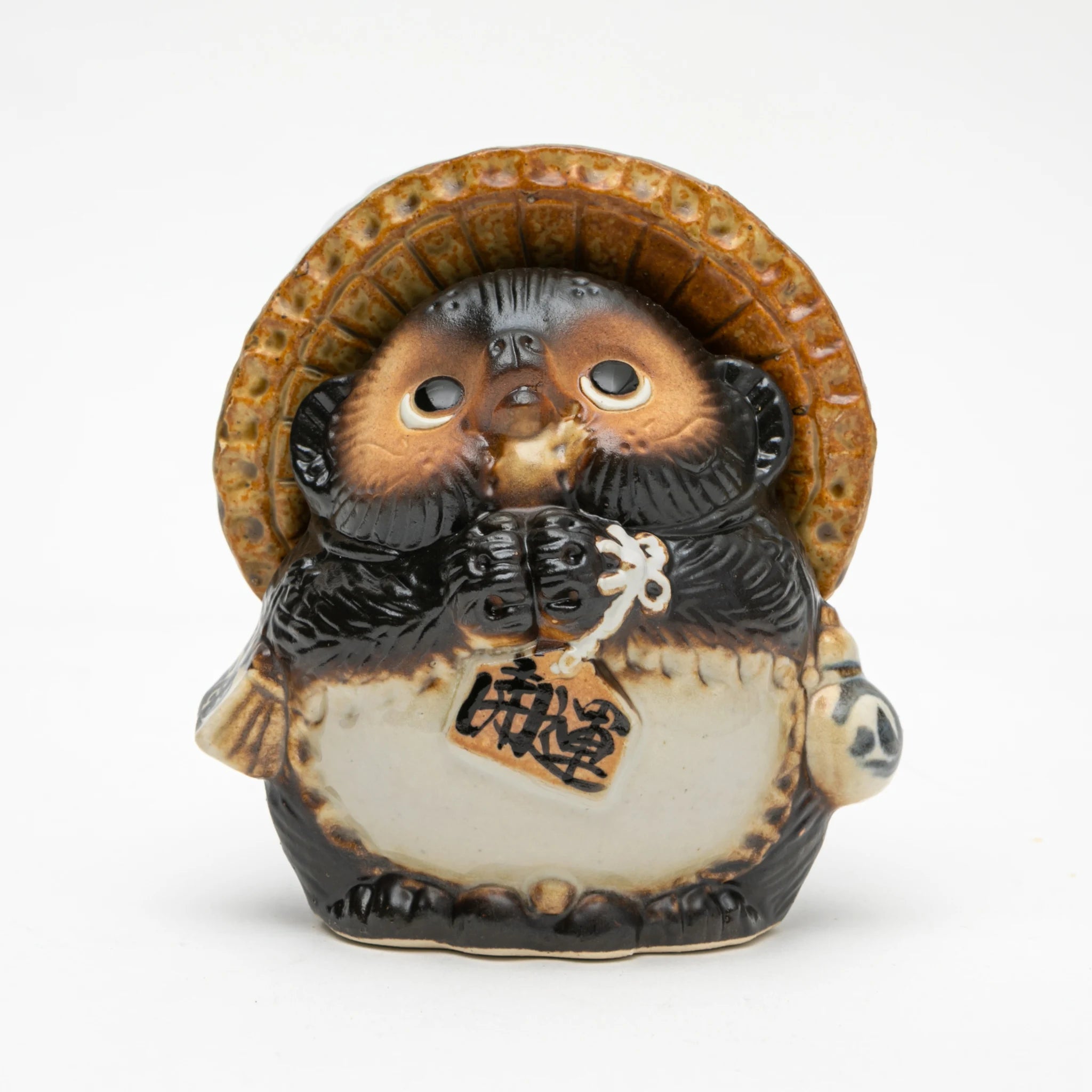 Front view of the Maruichi Shigaraki ware Wishing tanuki figurine, showing a compact round form with straw hat, paws clasped together holding a small ema wishing tablet, and wide-eyed upward expression.