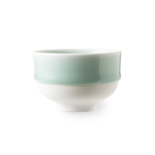 Side view of a Nabeshima Celadon porcelain tea cup with a green glaze and a white base against a white background.