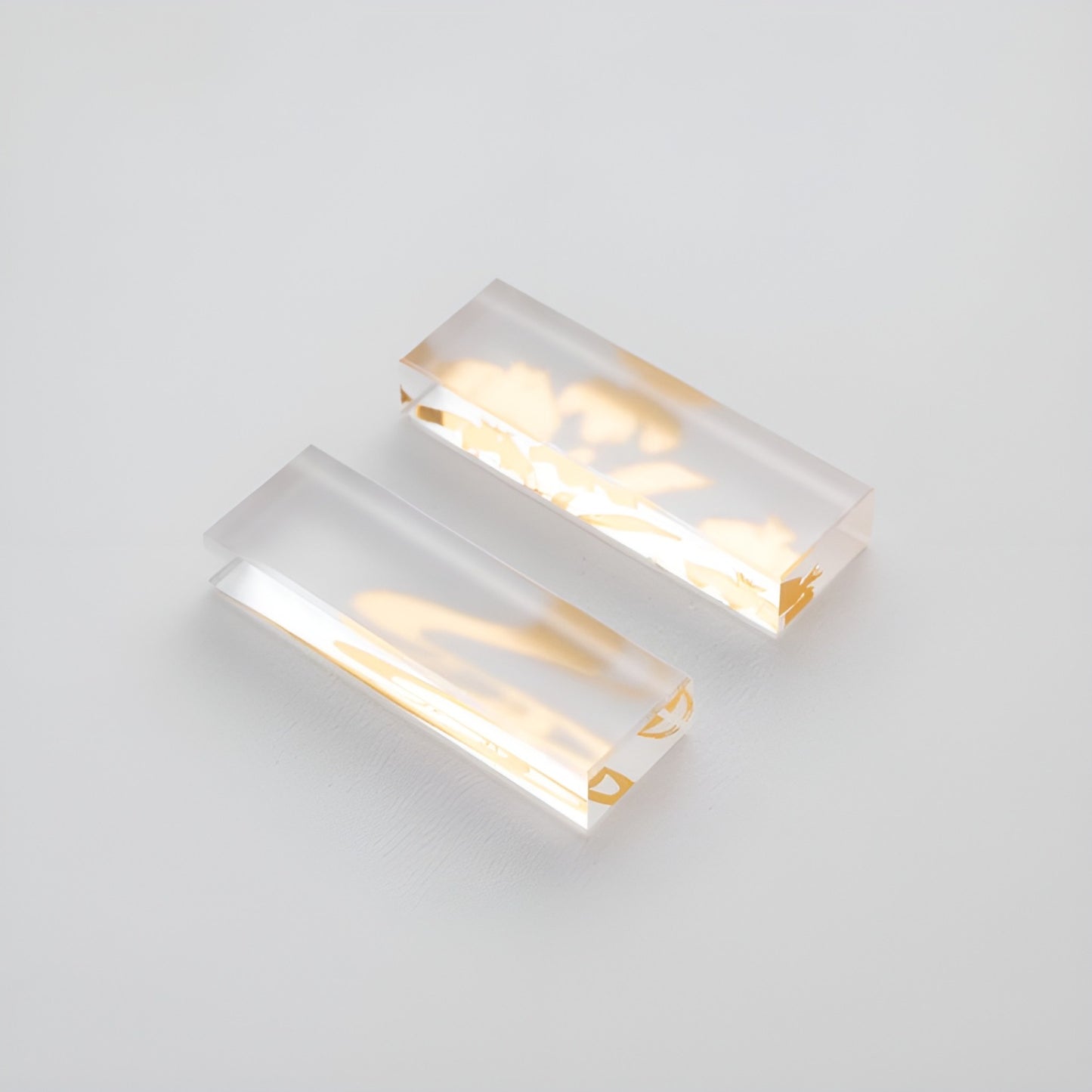 Close-up of two transparent chopstick rests with golden decorative patterns embedded inside, offering an elegant and refined touch.