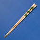 Natural wood chopsticks adorned with a pine tree design, showcasing leaves intertwined with golden accents.