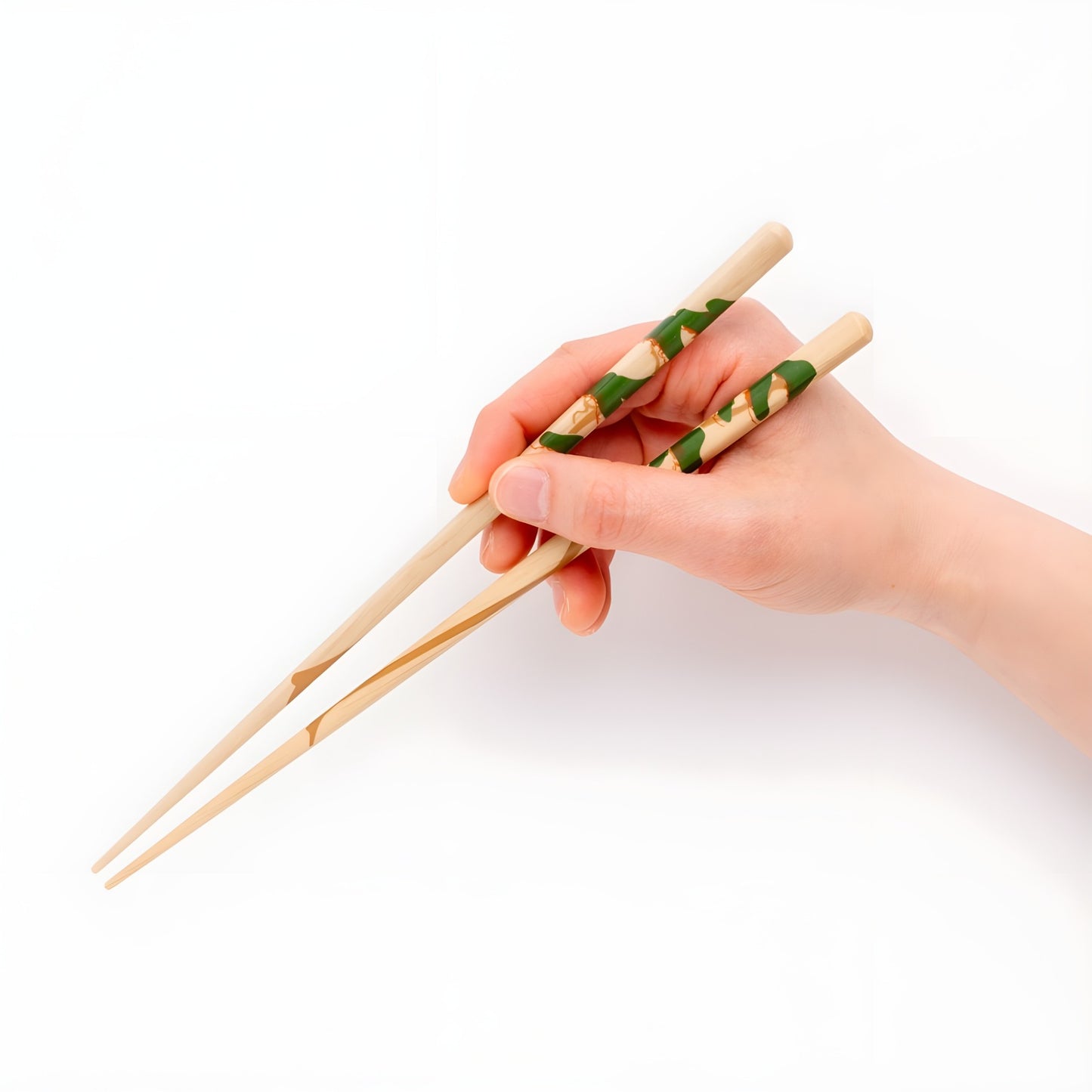 A hand holding natural wood chopsticks with a green pine tree motif, highlighting the detailed and serene design.