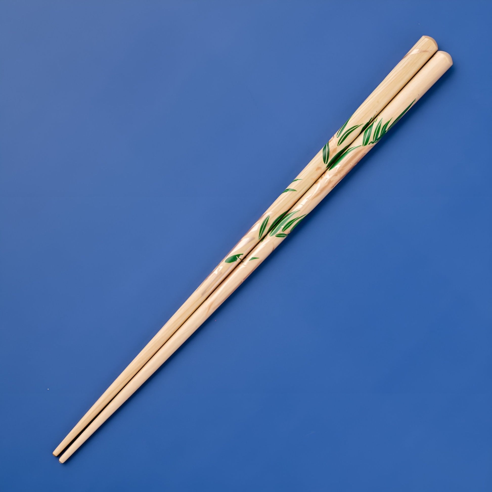 Close-up of Rimpa-style chopsticks featuring a minimalistic bamboo leaf design, with rich green leaves painted on a light bamboo background.