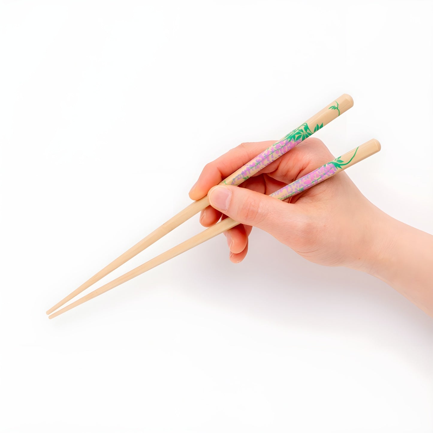 A hand holding Rimpa-style chopsticks featuring delicate wisteria flower designs, showcasing the elegant purple floral artwork against a natural wood background.