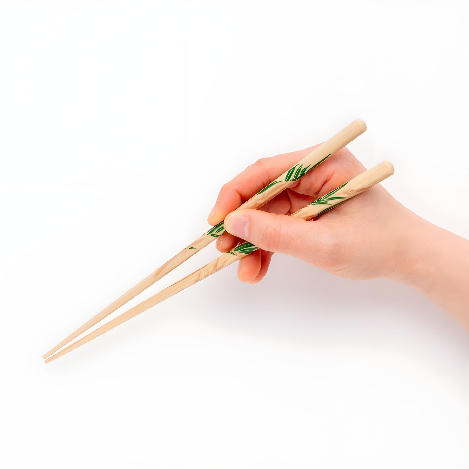 A hand holding Rimpa-style chopsticks featuring a minimalistic bamboo leaf design with green leaves on a light natural wood background.