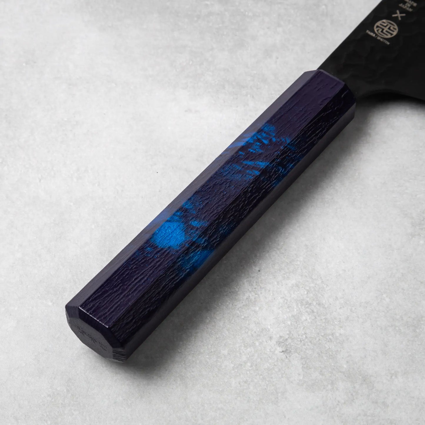 A detailed view of the burgundy resin handle of the Sakai Takayuki Kurokage VG10 petty knife, highlighting its smooth finish and subtle marbled design.