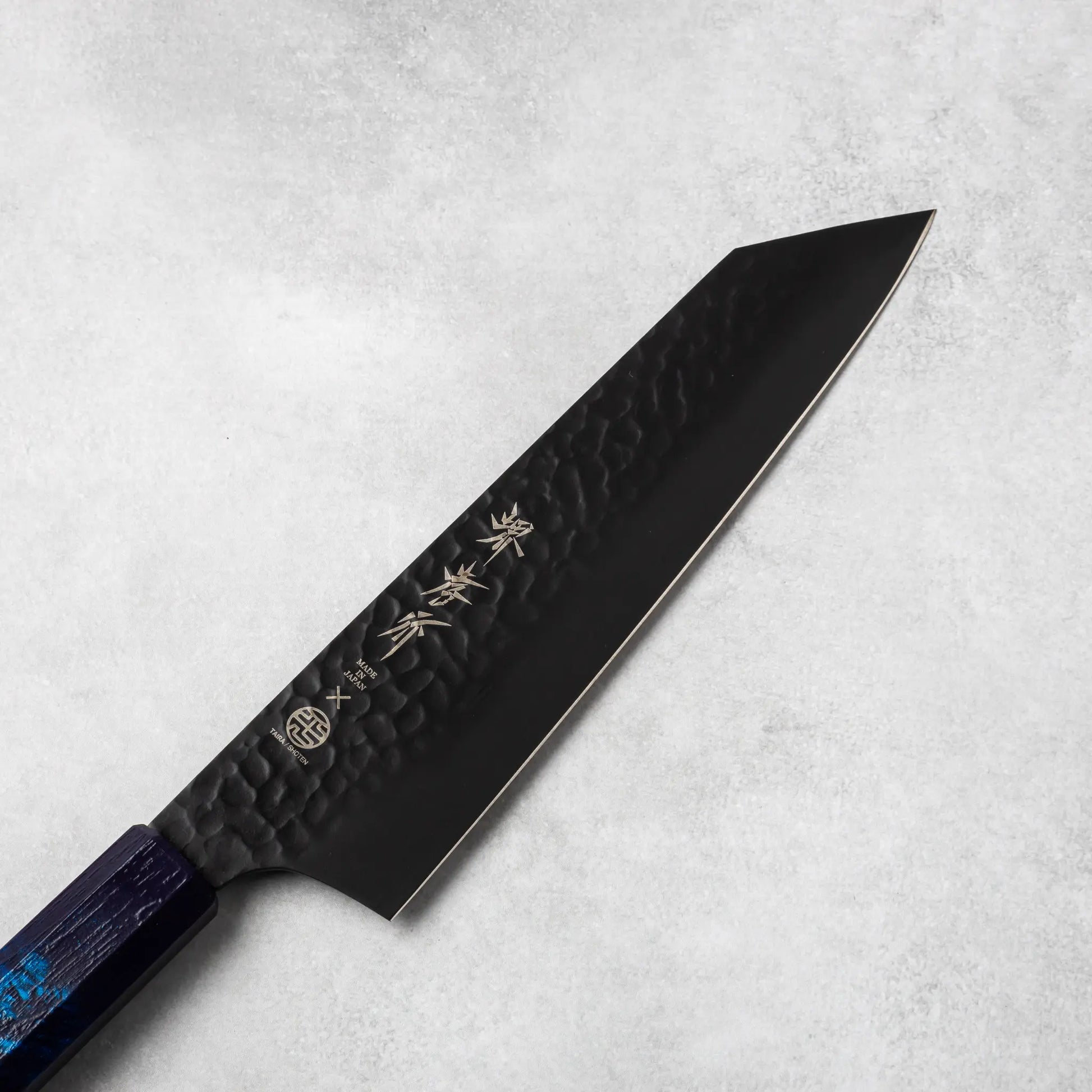 Close-up view of the Sakai Takayuki Kurokage VG10 petty knife's blade, showcasing the hammered texture and engraved Japanese kanji lettering.