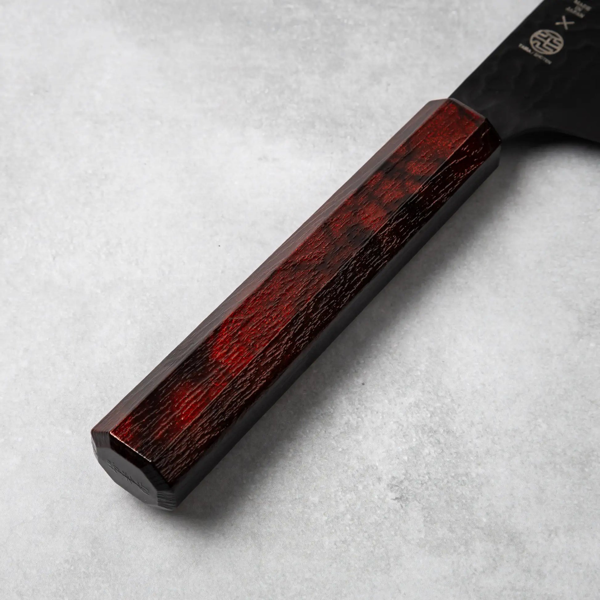 A detailed view of the burgundy resin handle of the Sakai Takayuki Kurokage VG10 Kengata chef knife, with subtle marbled patterns and a smooth octagonal design.