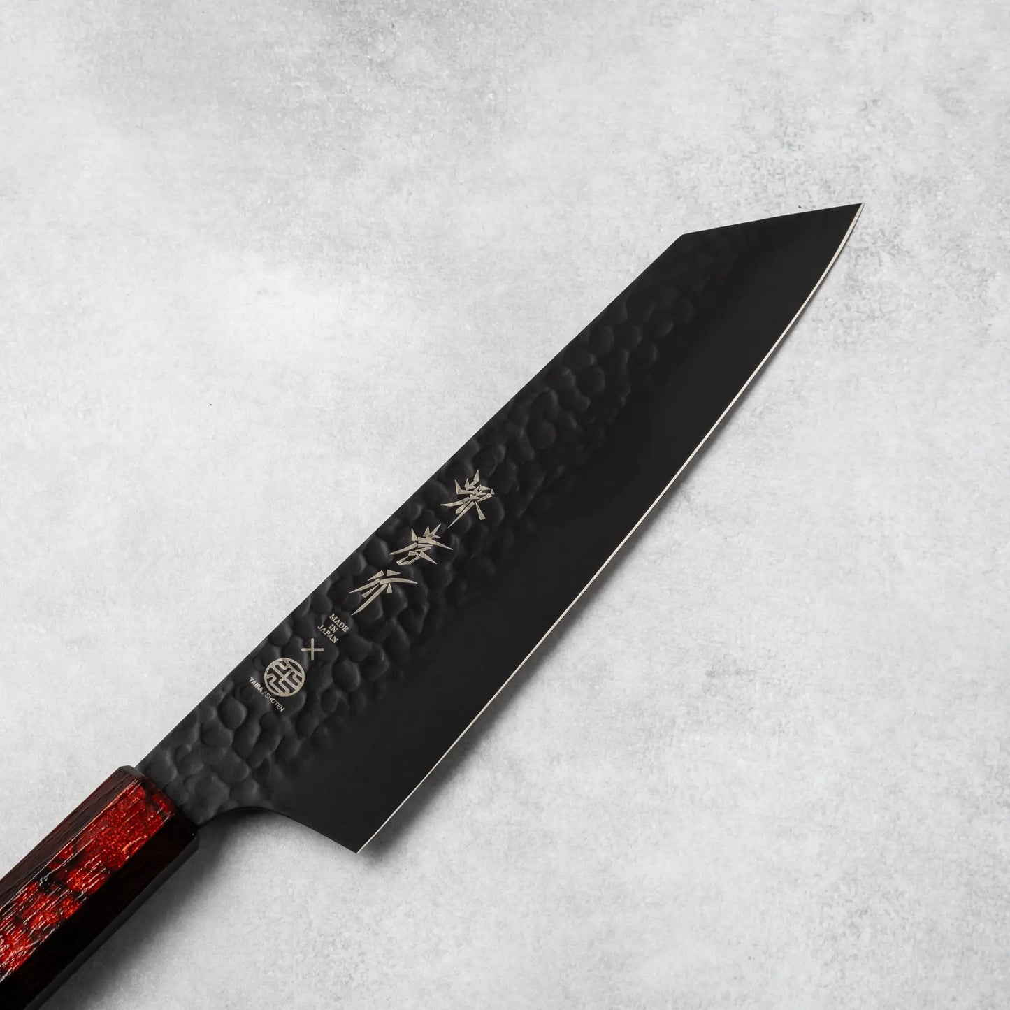 Close-up view of the Sakai Takayuki Kurokage VG10 Kengata chef knife's blade, showcasing its hammered texture, engraved Japanese kanji lettering, and sharp tapered tip.