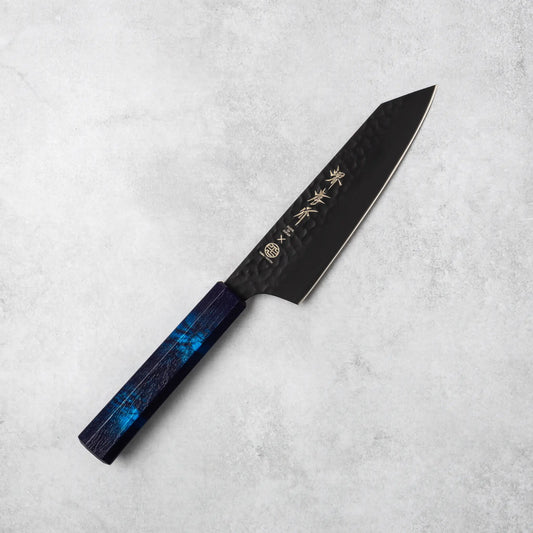 Sakai Takayuki Kurokage VG10 Kengata Santoku Knife showcasing its hammered black VG10 steel blade and vibrant blue handle, laid flat on a light stone surface