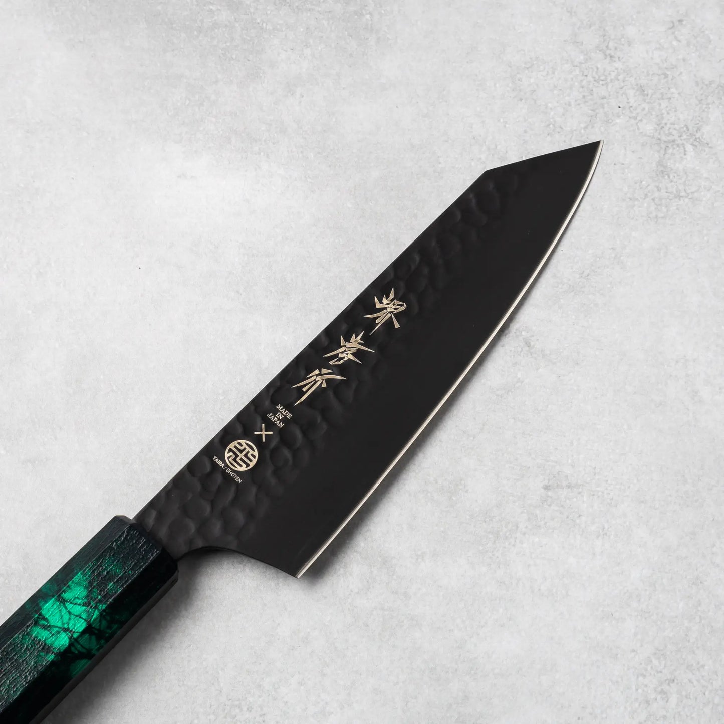 Close-up of the Sakai Takayuki Kurokage VG10 Kengata Santoku Knife's blade showcasing its hammered finish and intricate engraving.