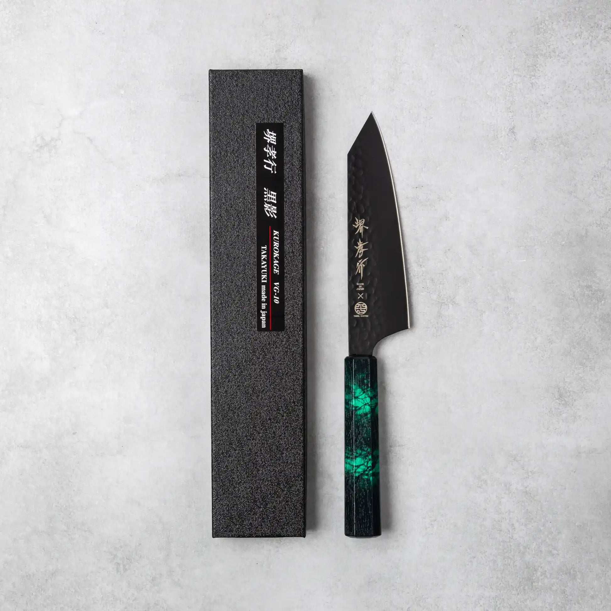 Sakai Takayuki Kurokage VG10 Kengata Santoku Knife with a green handle and its packaging displayed on a gray background.