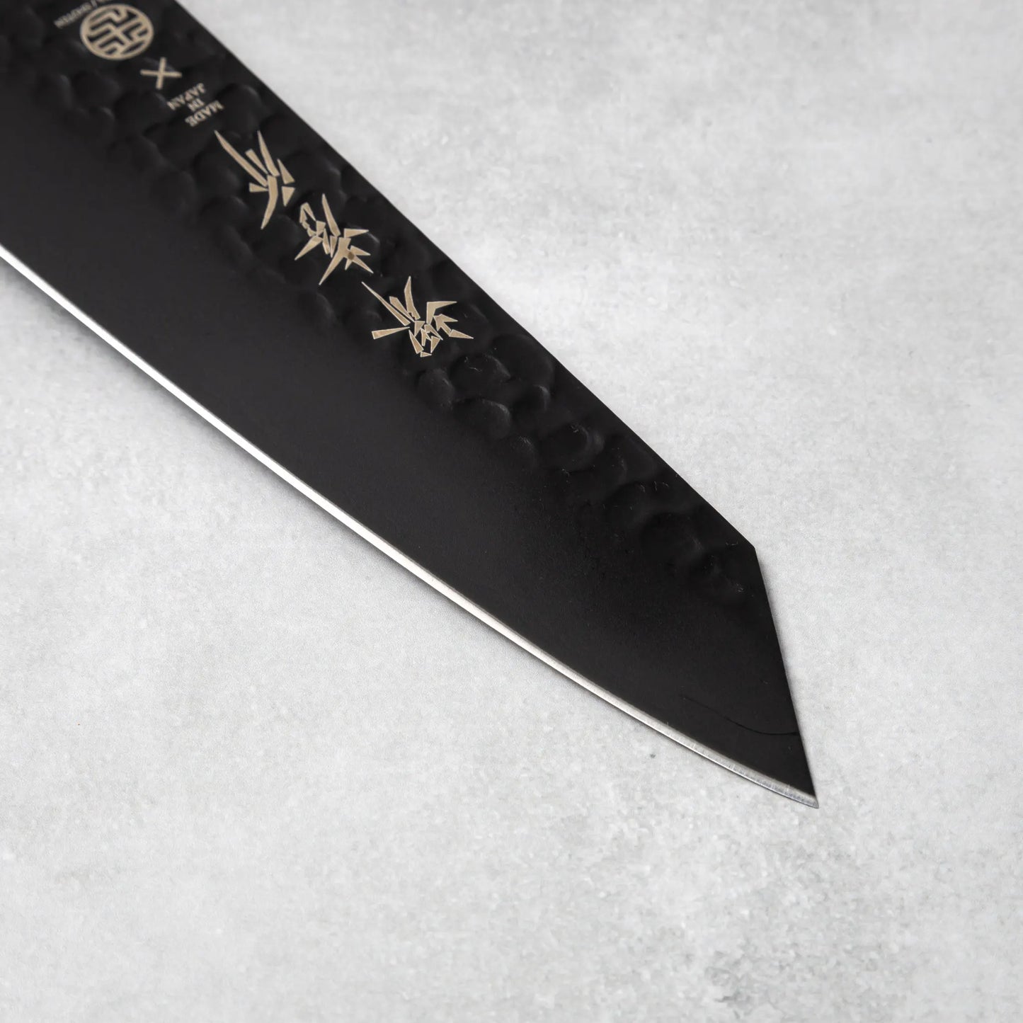 Detailed view of the blade tip of the Sakai Takayuki Kurokage VG10 Kengata Santoku Knife emphasizing its sharp edge and hammered texture.