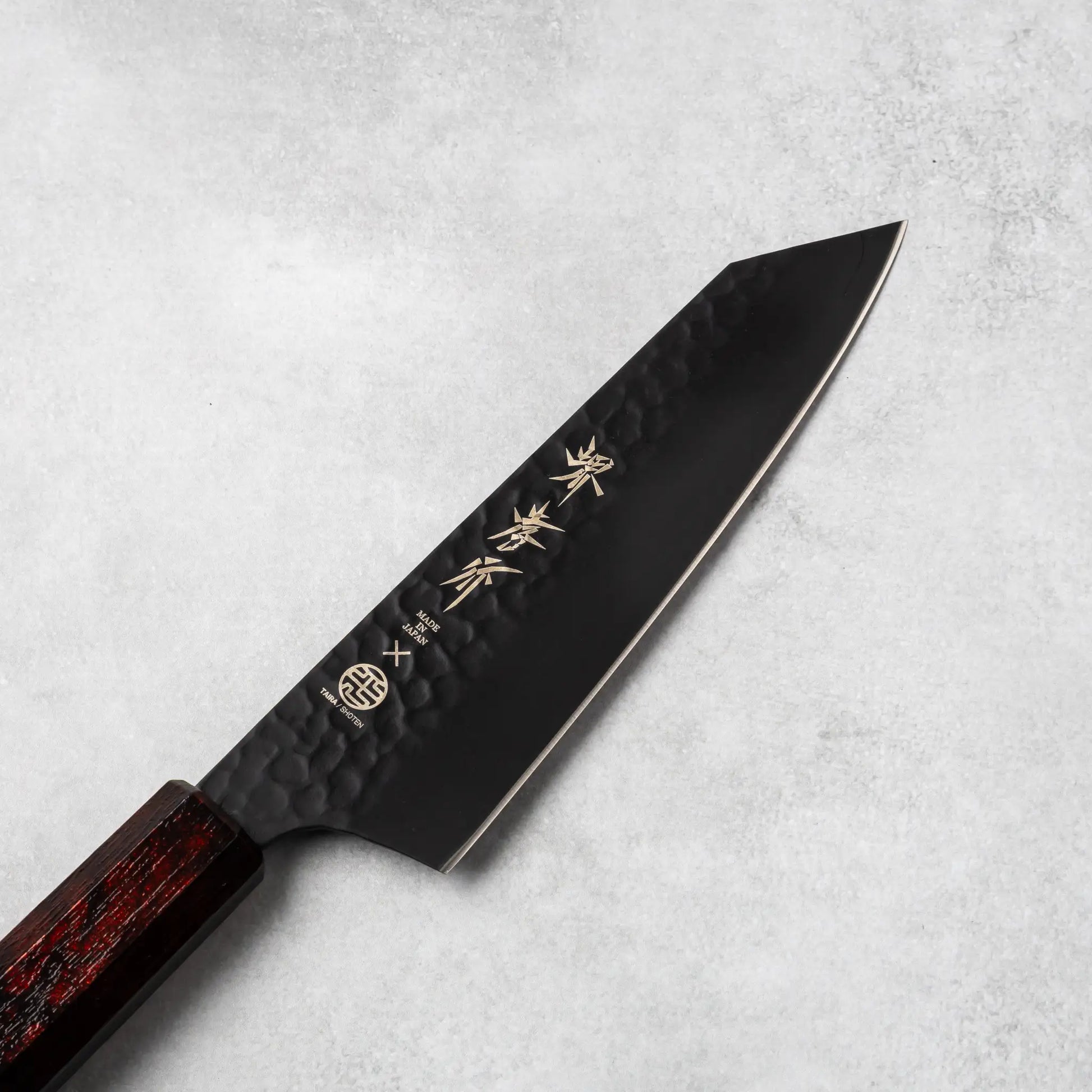 Close-up of the hammered black blade of the Sakai Takayuki Kurokage VG10 Kengata Santoku Knife highlighting its Japanese kanji engravings.