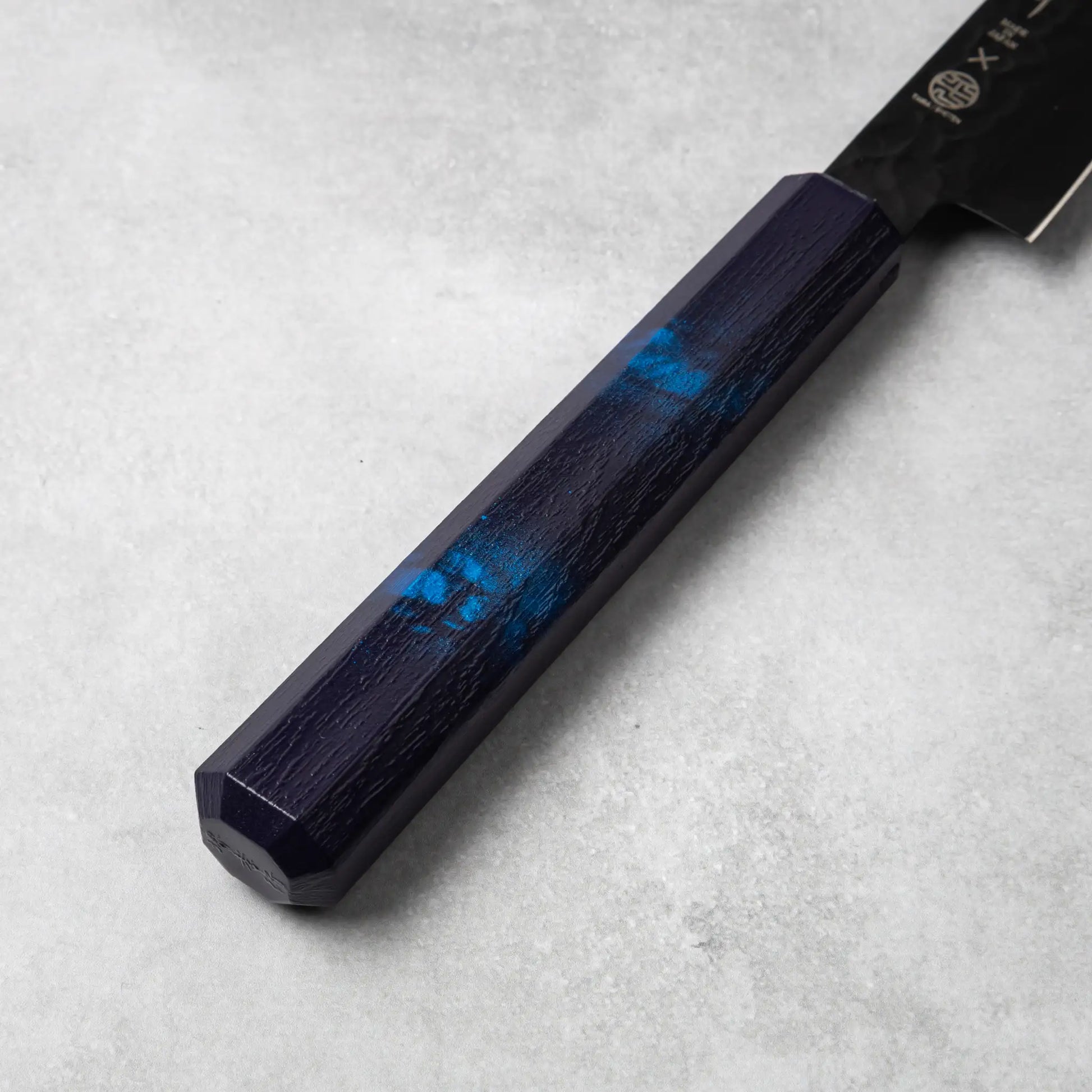 A detailed view of the blue resin handle of the Sakai Takayuki Kurokage VG10 petty knife, showing the subtle marbled blue accents and smooth texture.