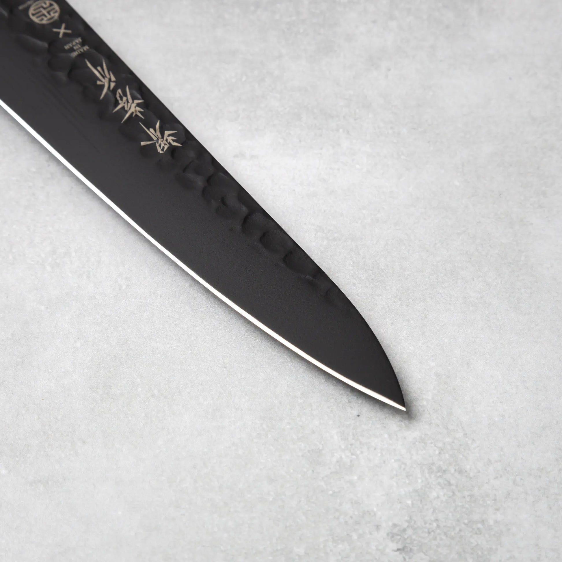 The tapered blade tip of the Sakai Takayuki Kurokage VG10 petty knife, emphasizing the sharp precision edge and hammered detailing.