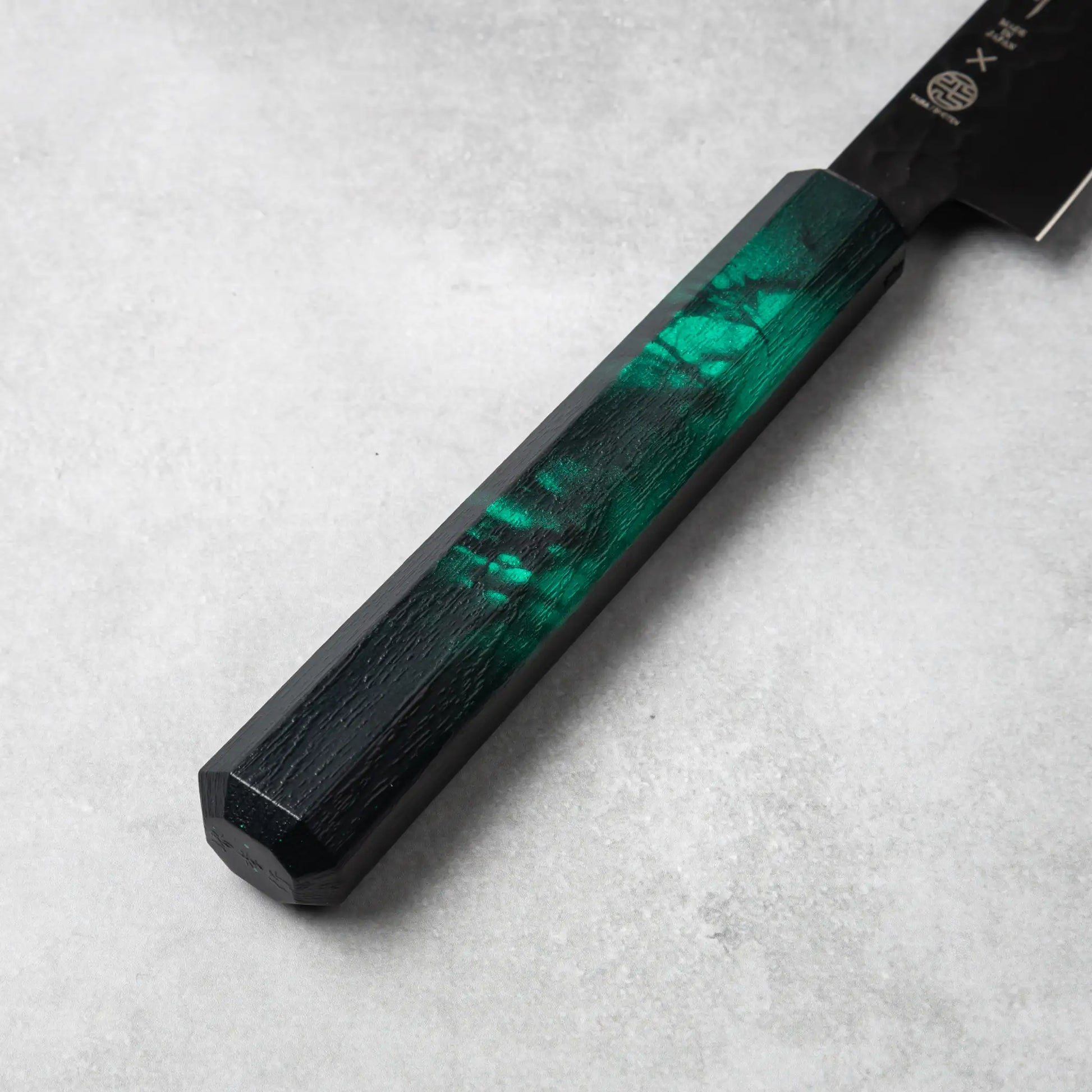 A detailed view of the green resin handle of the Sakai Takayuki Kurokage VG10 petty knife, highlighting its smooth texture and subtle marbled accents.