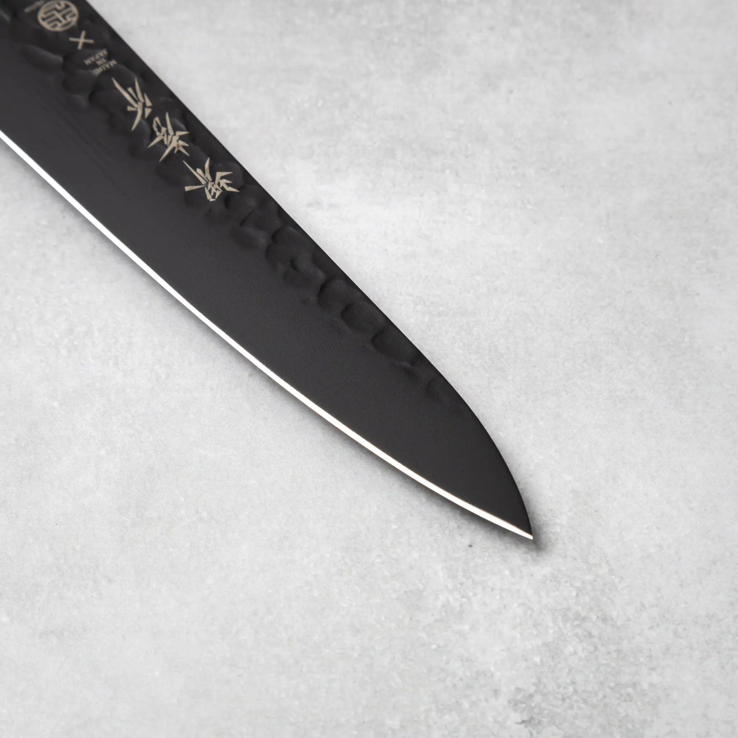 The sharp blade tip of the Sakai Takayuki Kurokage VG10 petty knife, showcasing its precision edge and hammered surface.