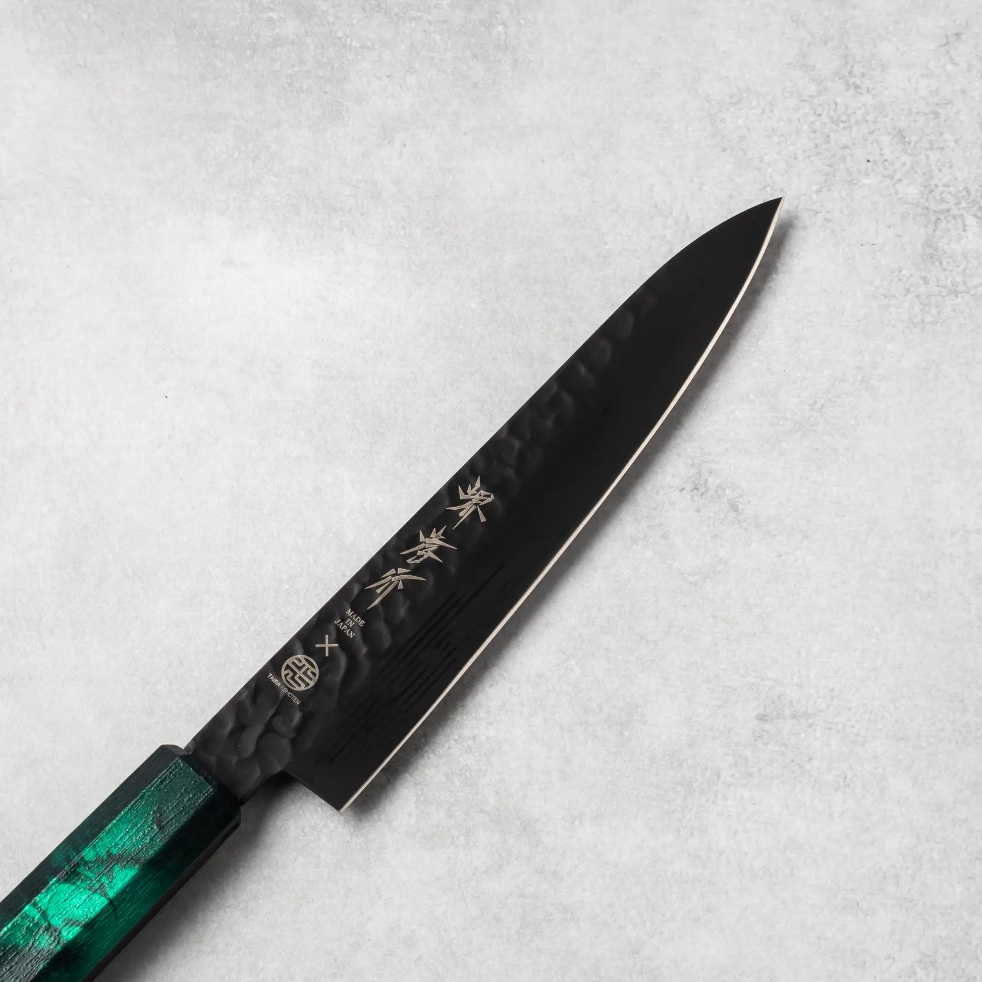 Close-up view of the Sakai Takayuki Kurokage VG10 petty knife's blade, emphasizing the hammered texture and engraved Japanese kanji lettering.