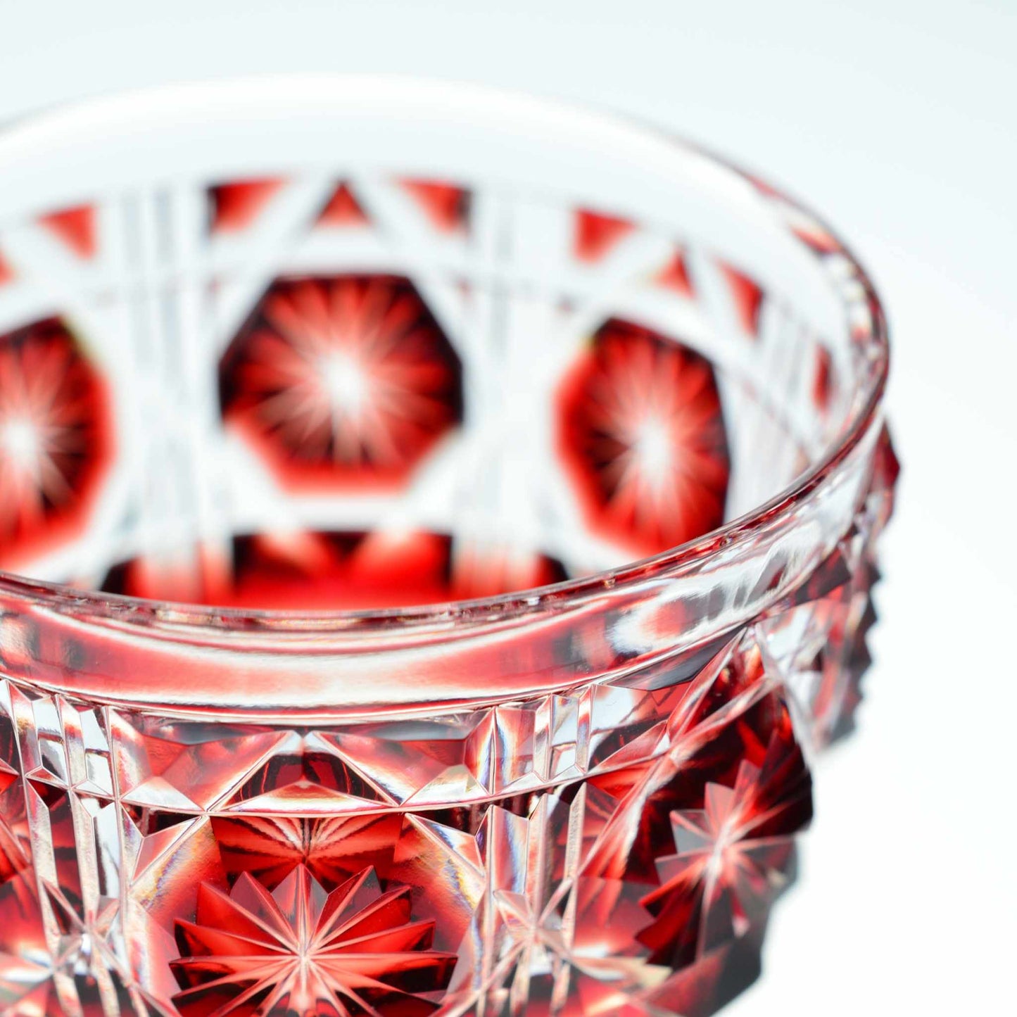 Close-up of crimson Satsuma Kiriko sake cup showcasing craftsmanship and starburst pattern.