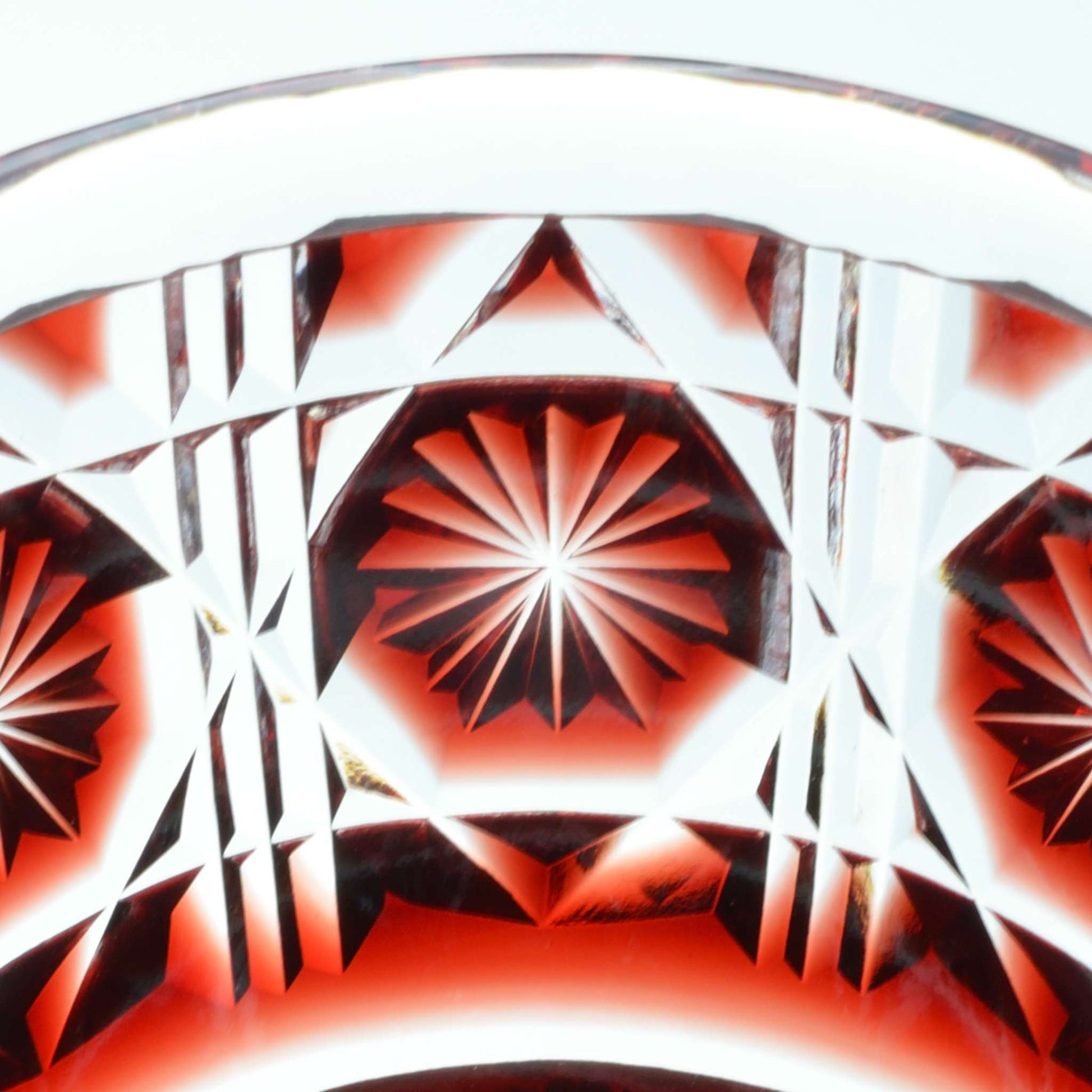 Close-up of intricate starburst pattern on crimson Satsuma Kiriko sake cup.