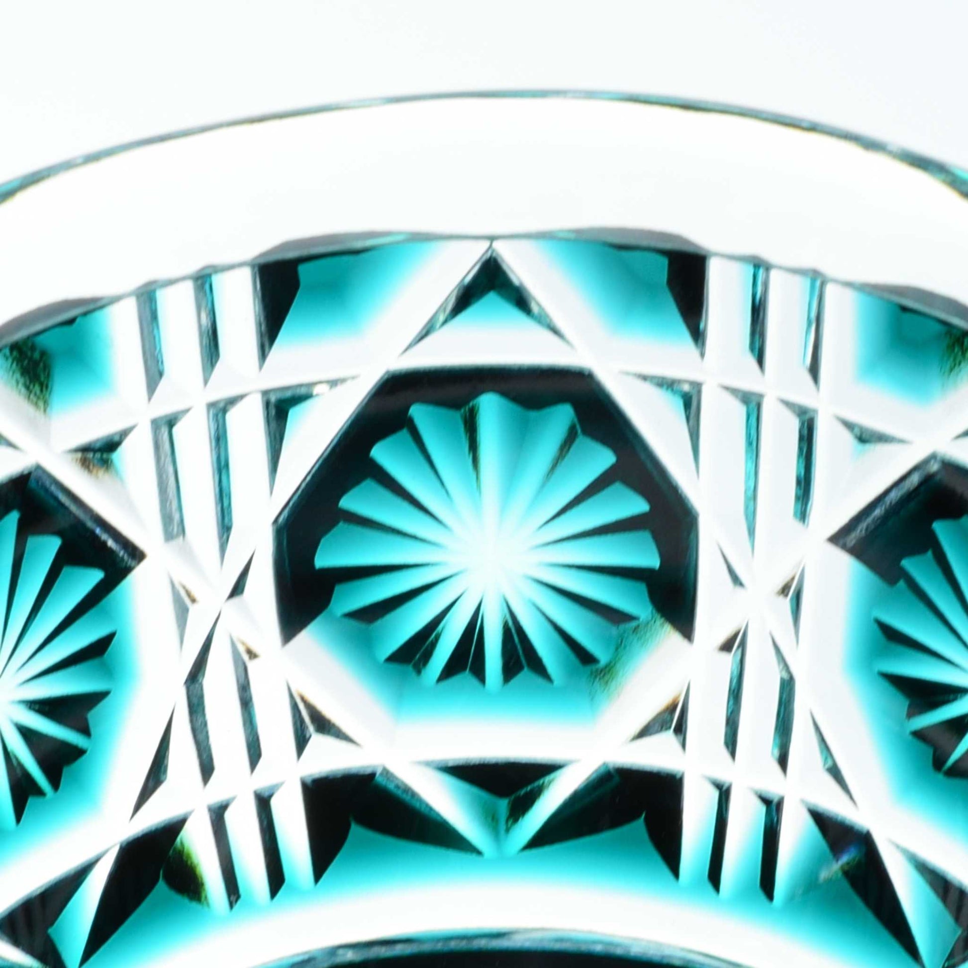 Close-up of intricate starburst pattern on green Satsuma Kiriko sake cup.