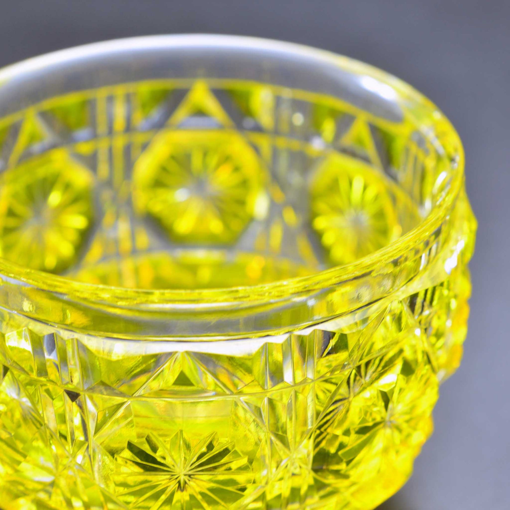 Close-up of Satsuma Kiriko yellow sake cup showing its craftsmanship and geometric pattern.