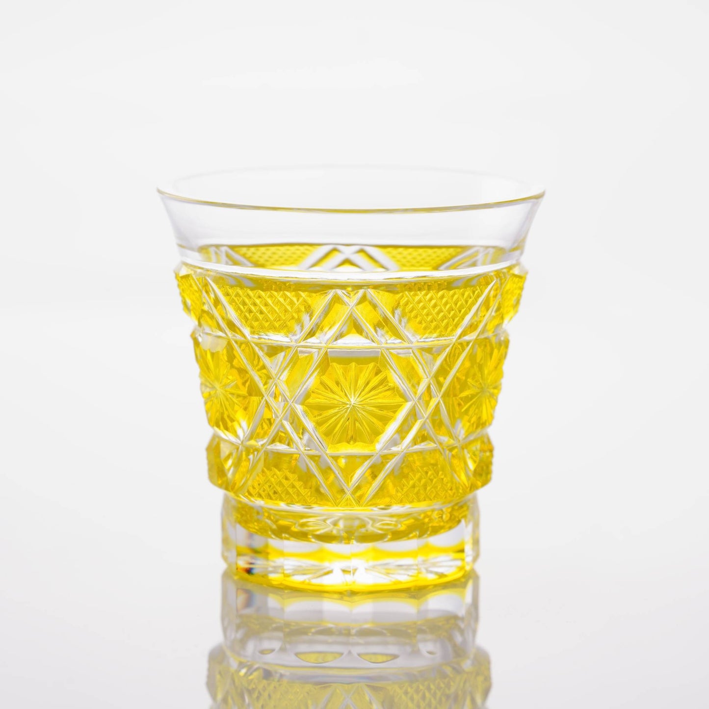 Full view of a Satsuma Kiriko two-tone yellow sake glass, reflecting intricate patterns and craftsmanship.