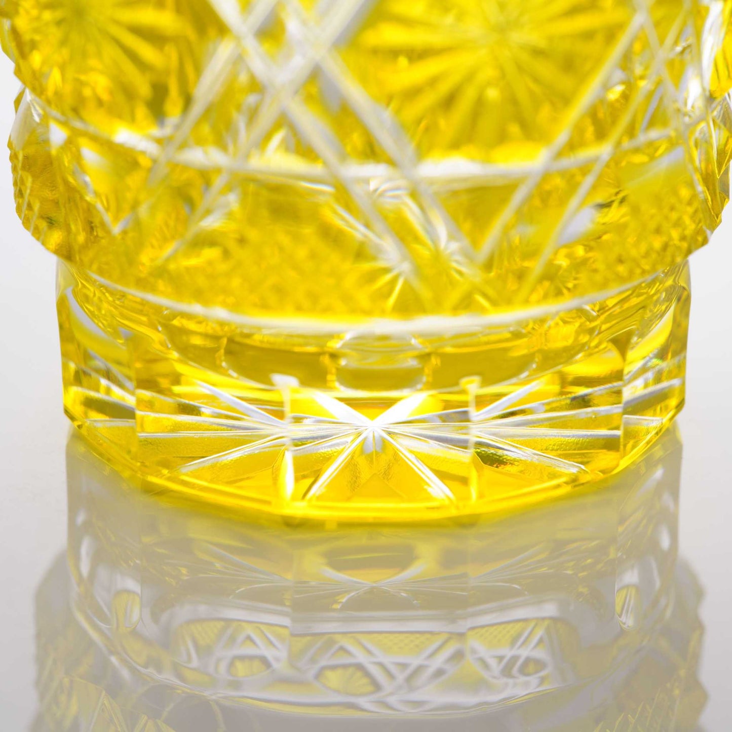 Close-up of the base of a Satsuma Kiriko two-tone yellow sake glass, highlighting etched geometric designs.