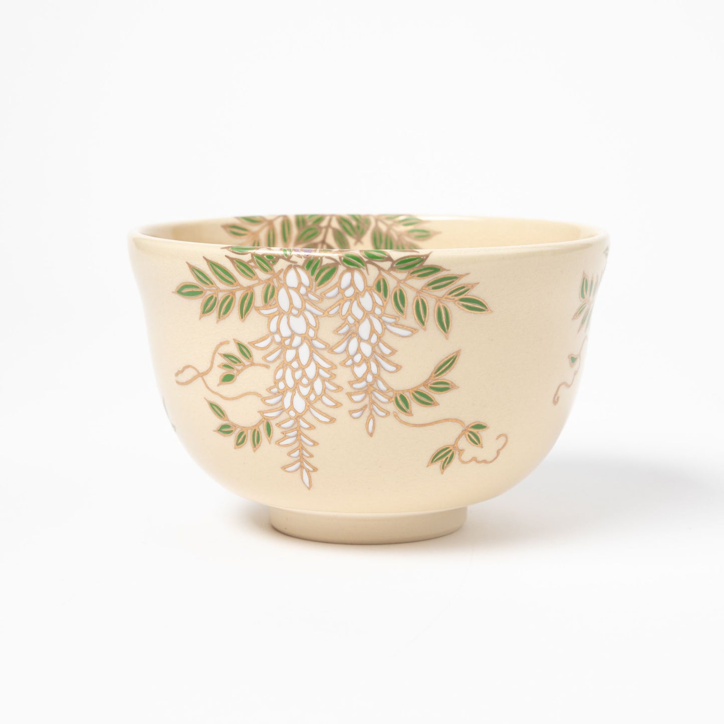 Side view of a cream-colored matcha bowl adorned with delicate wisteria patterns in green and purple, highlighting its intricate design.