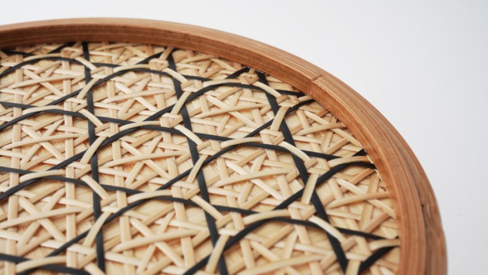 Intricately woven bamboo tray showcasing a detailed lattice pattern with a mix of natural bamboo and black accents, surrounded by a smooth wooden rim, highlighting the craftsmanship of Suruga Bamboo Sensuji Zaiku.